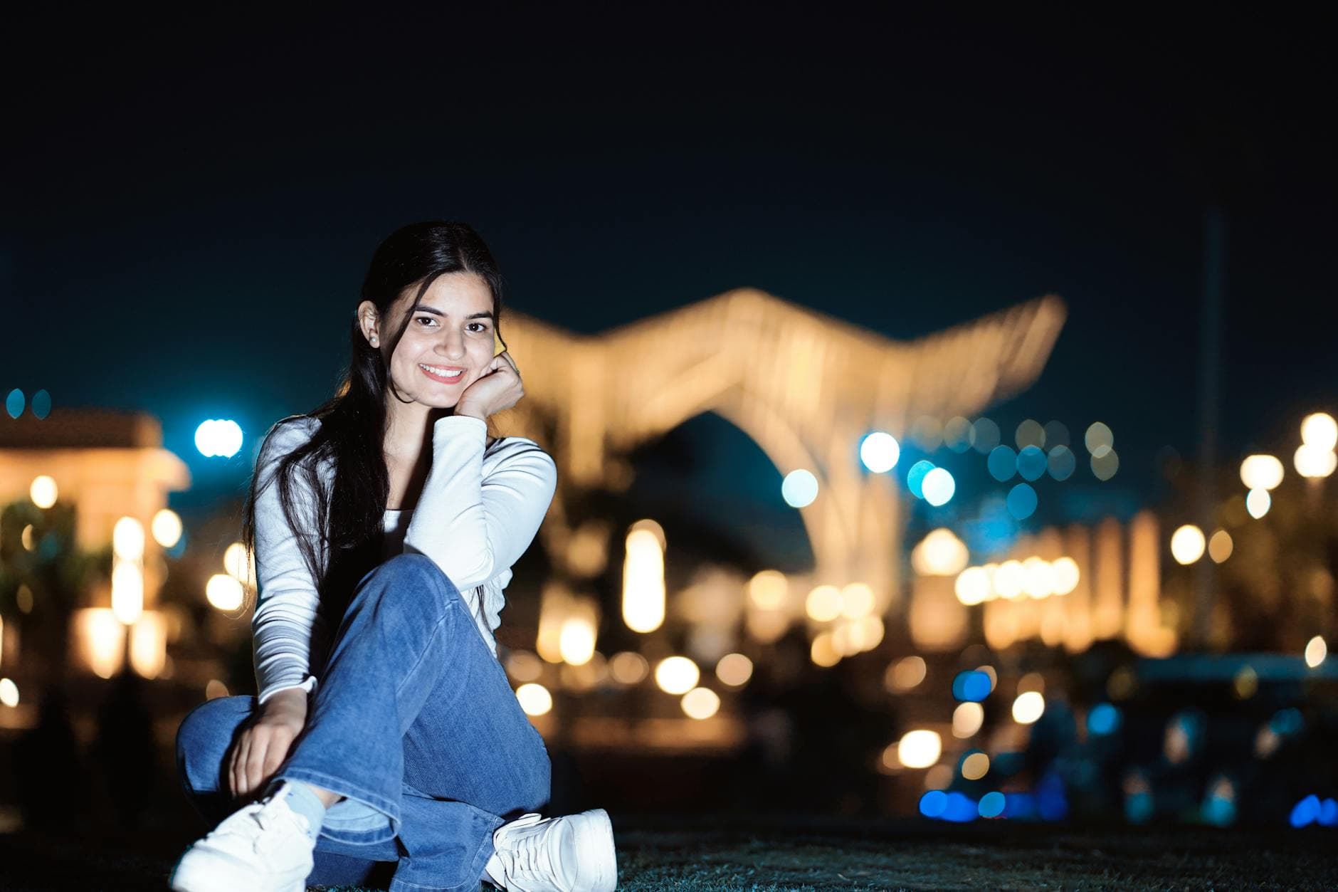 Portrait of a young woman smiling outdoors at night with city lights in the background. - how to apologize effectively