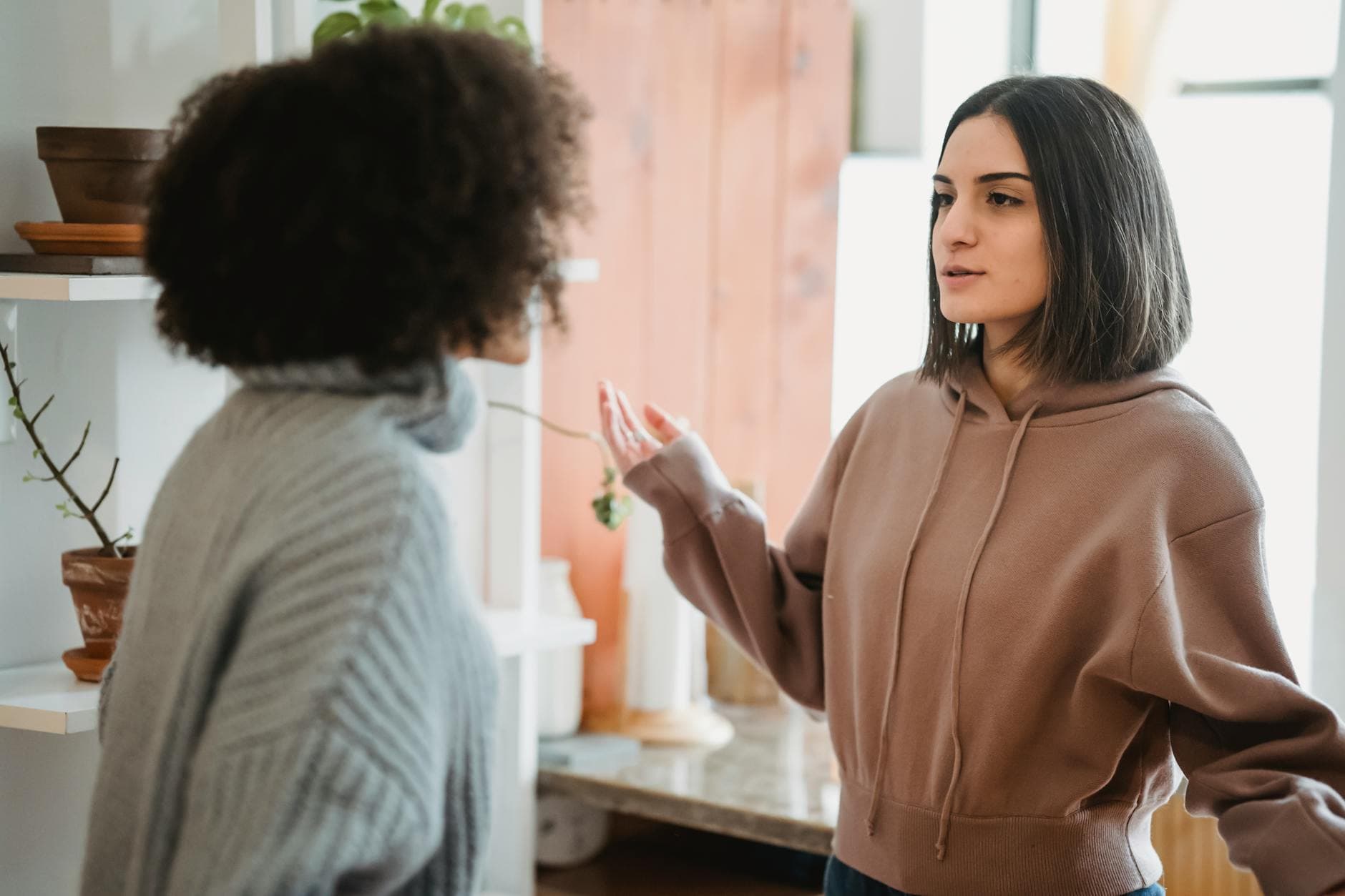 Two women engage in a serious conversation in a cozy indoor setting. - cbt for winter negative self-talk