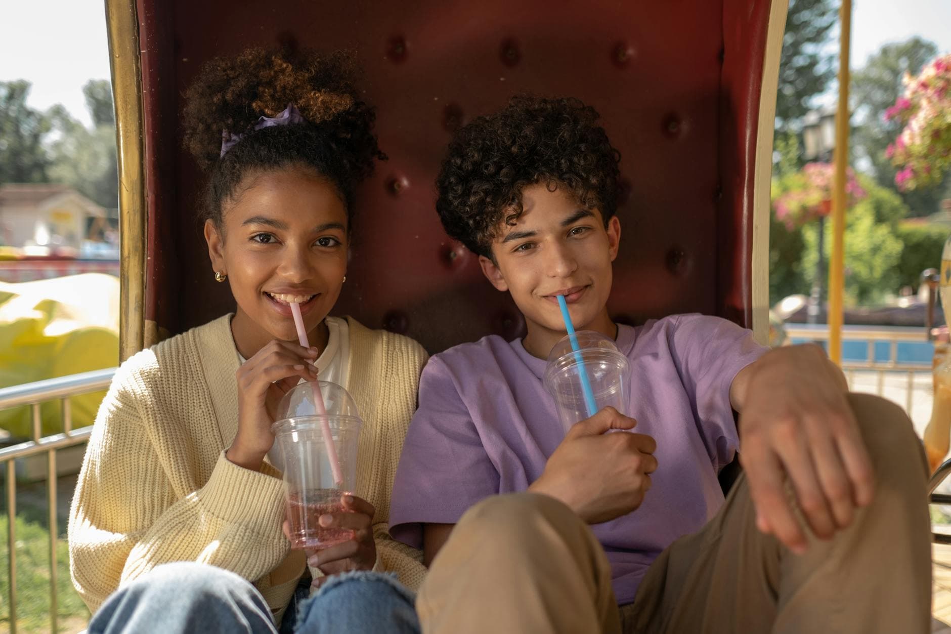 Smiling couple enjoying drinks on a sunny day at the amusement park. Perfect first date. - good first date questions