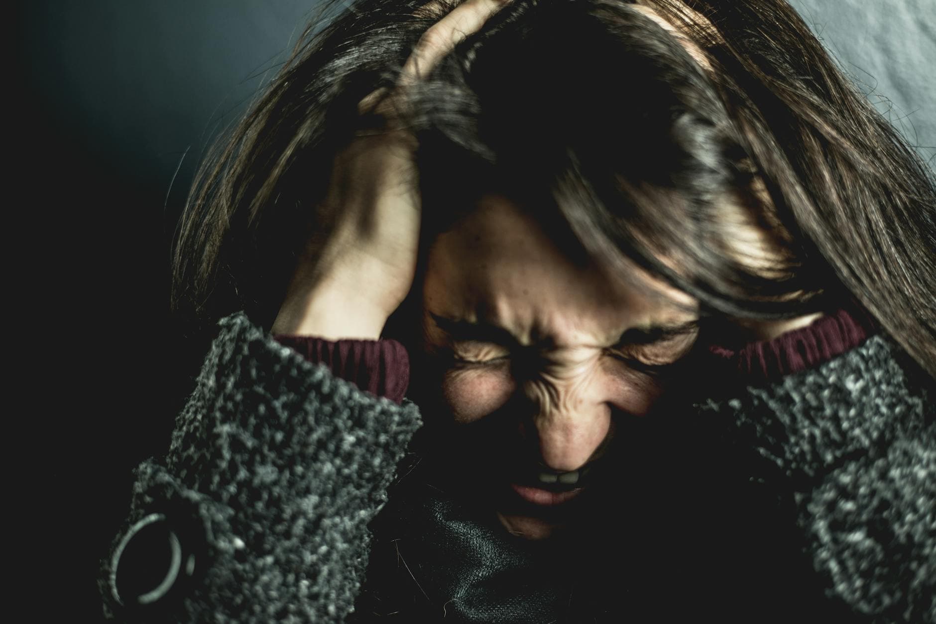 Close-up of a woman in distress with eyes closed and hands in hair, expressing anxiety. - manage kids winter frustration