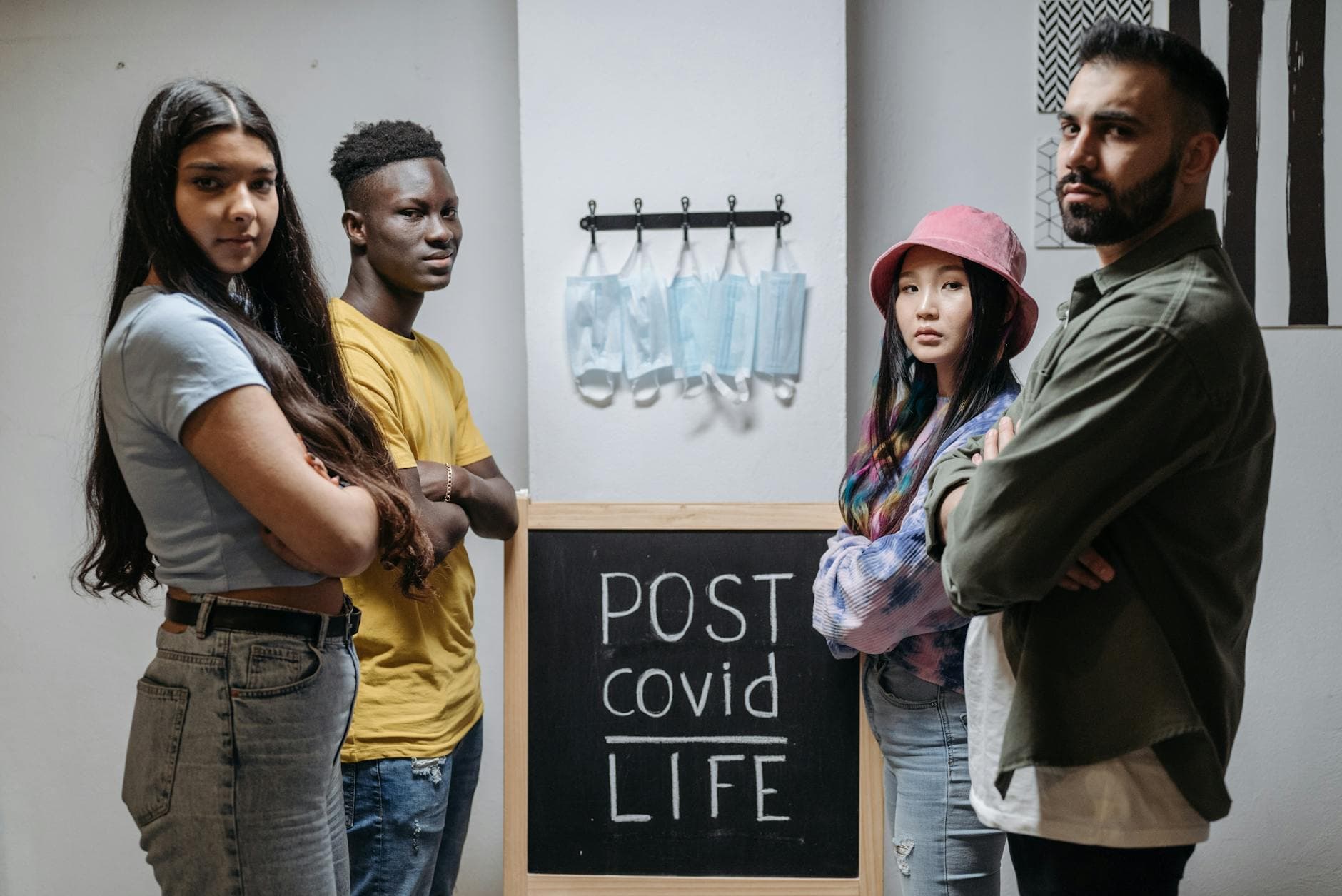 Diverse individuals standing in front of a chalkboard reading 'Post COVID Life' with hanging face masks. - rebuilding trust after affair