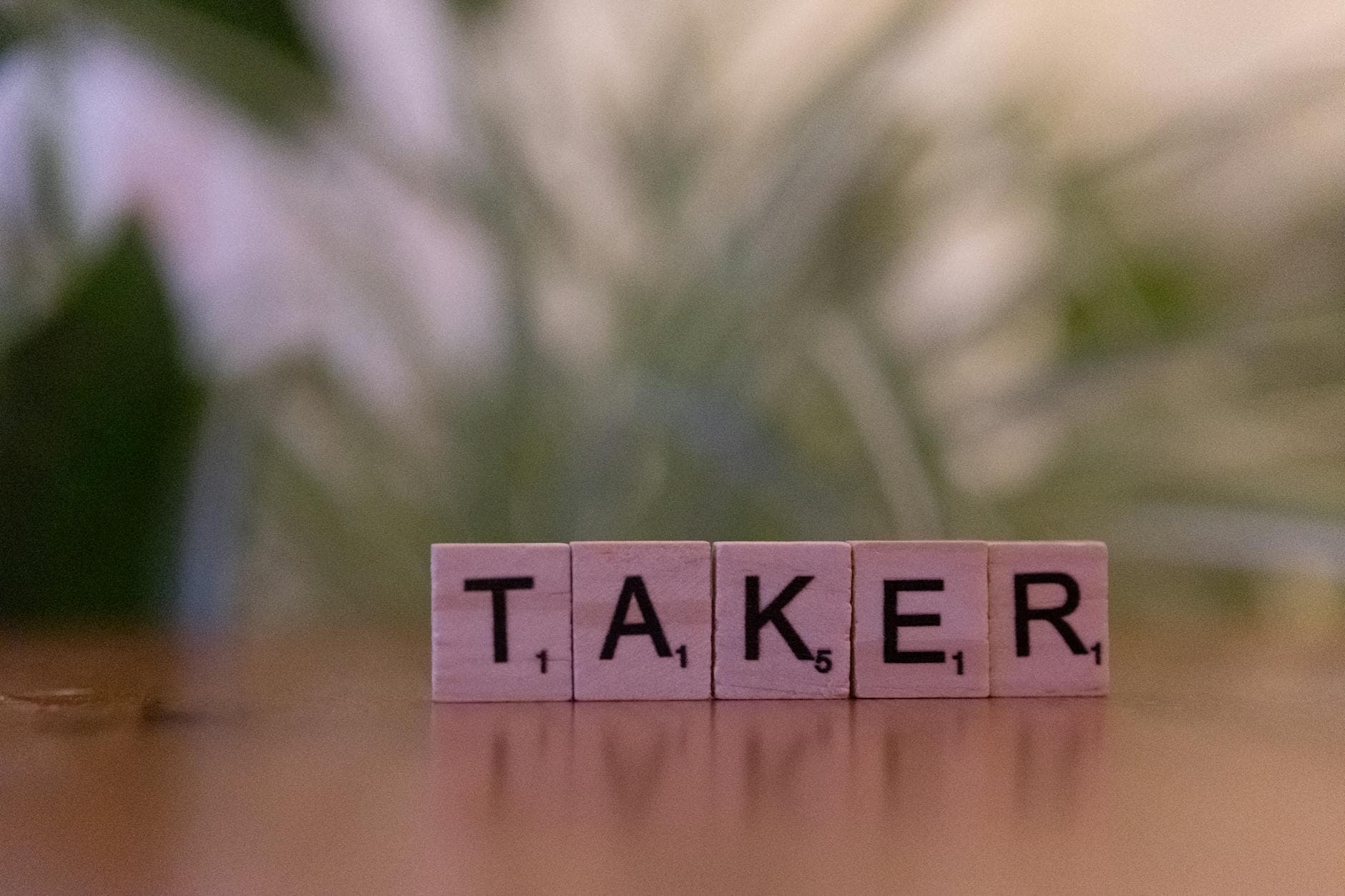 Close-up of Scrabble tiles spelling 'taker' on a blurred background, focus on letters. - signs of narcissist partner