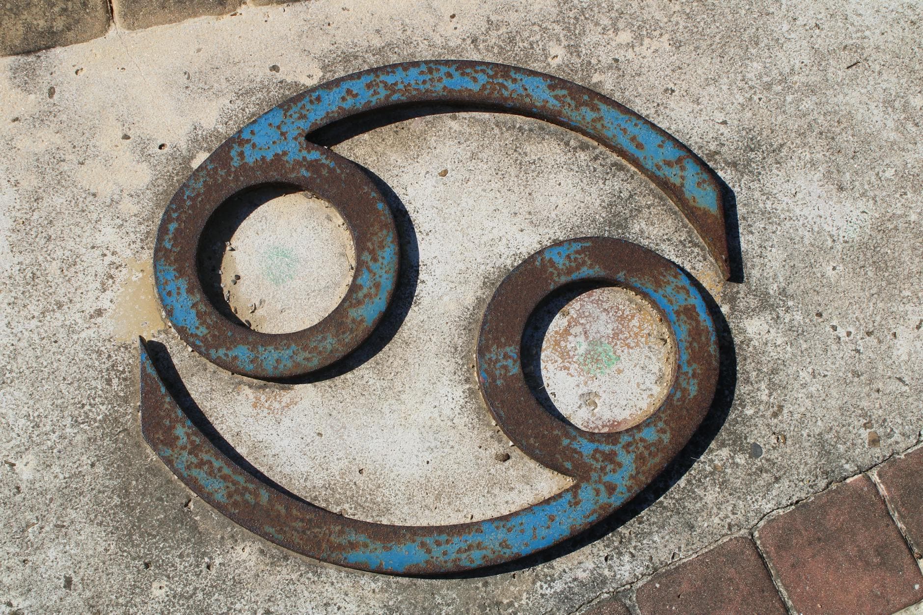 Close-up of a rusted Cancer zodiac symbol on a concrete wall. - toxic relationship zodiac signs