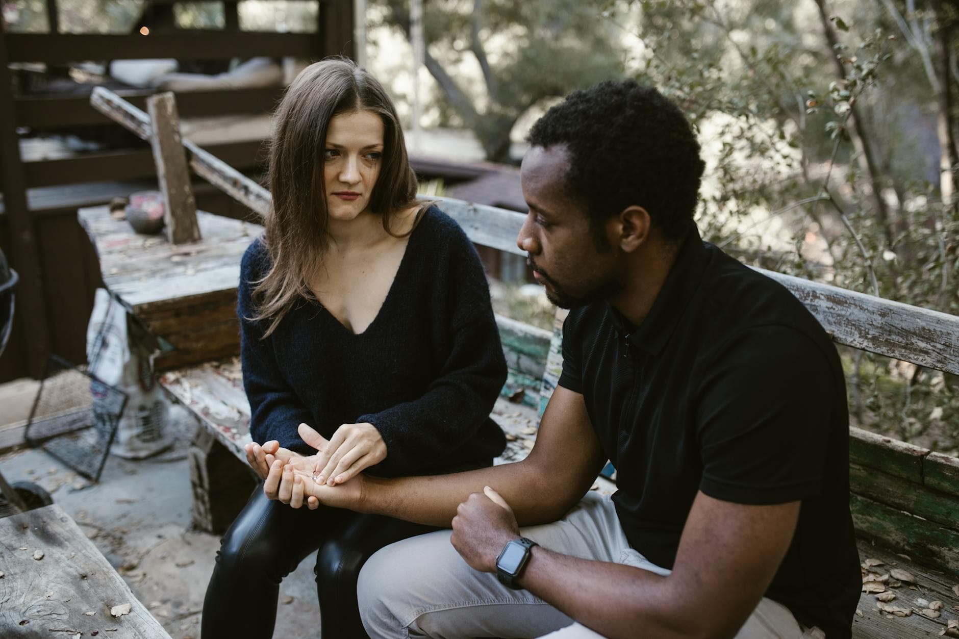 A couple in an emotional conversation on a rustic outdoor bench, conveying tension and concern. - active listening difficult conversations