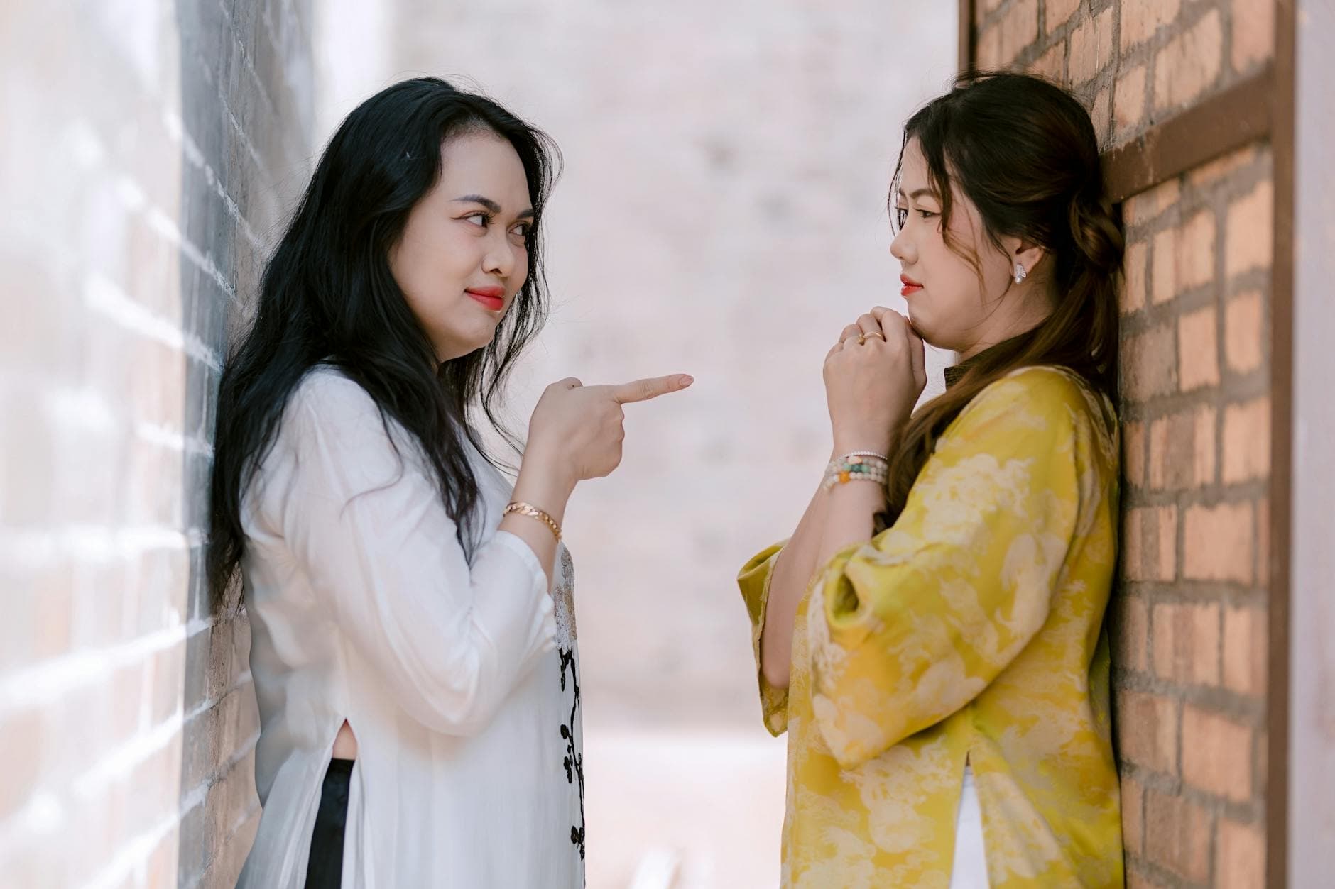 Two women interact in a narrow alleyway with a playful stance, bringing attention to their expressions. - assertive communication meaning