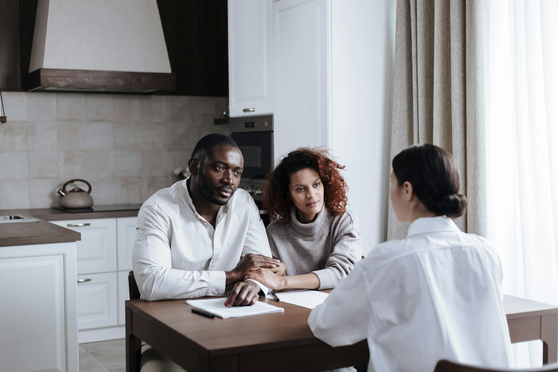 A couple discusses adoption with a social worker in a modern kitchen setting. - couple travel planning communication