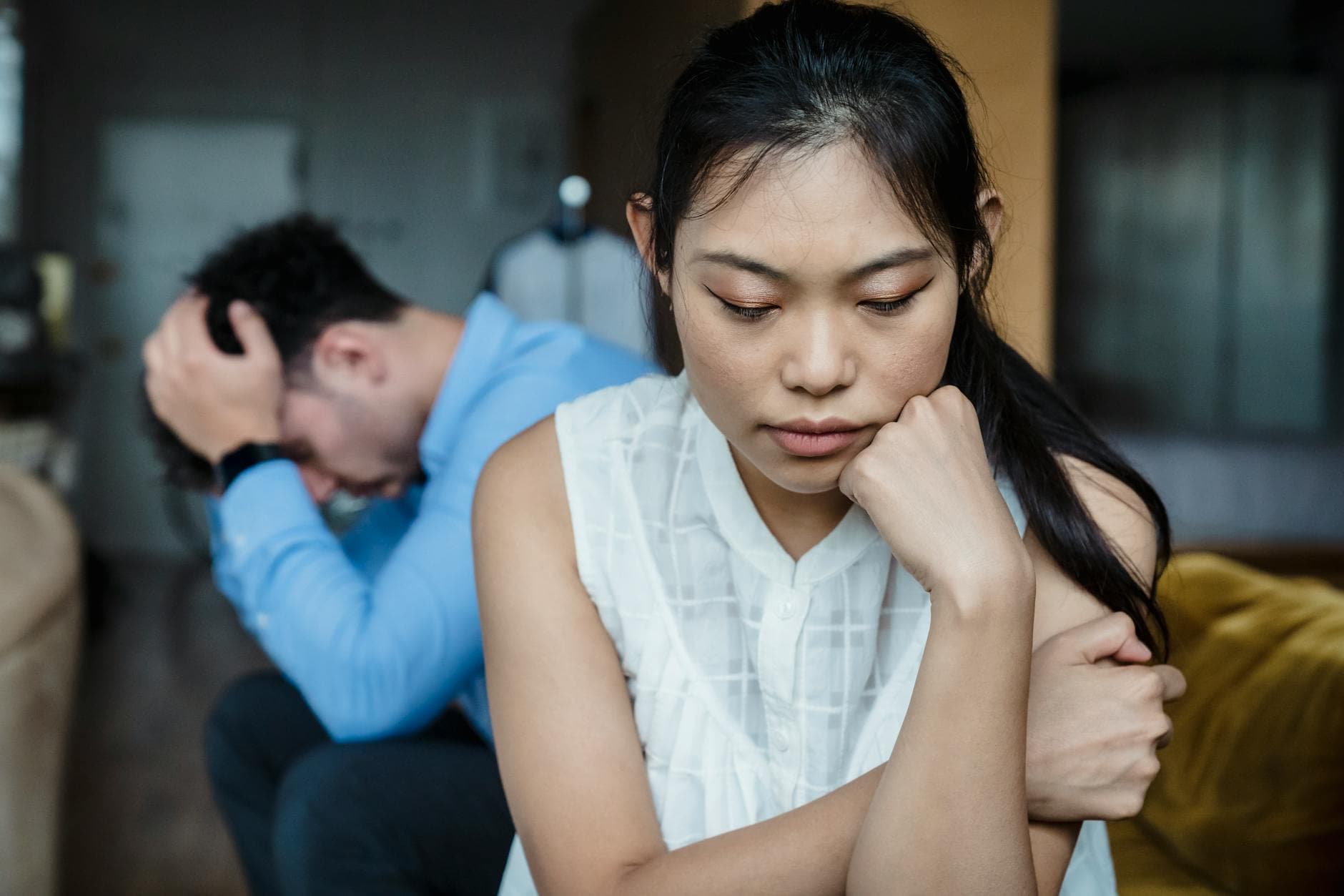 A couple experiencing relationship tension sitting silently on a sofa. - declutter negative thoughts