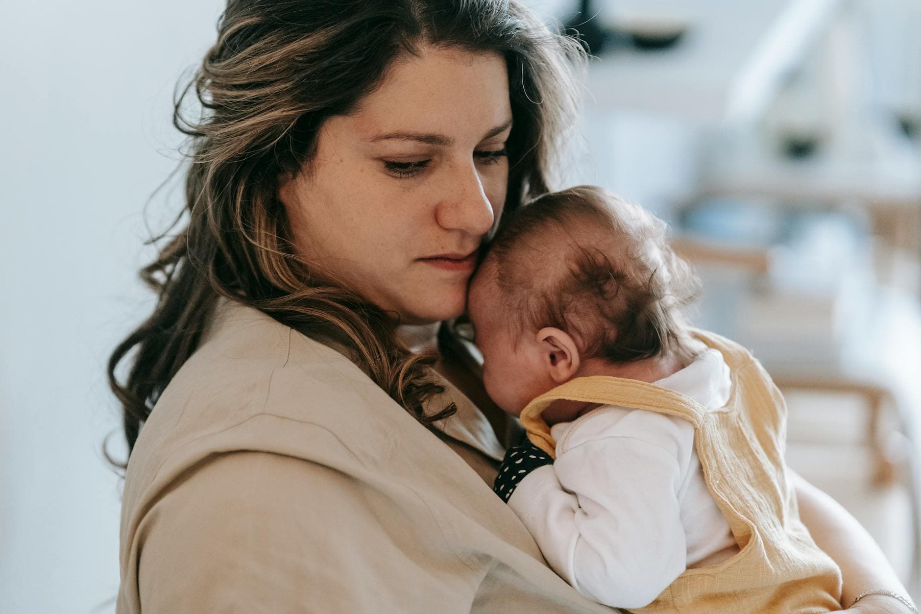 A mother gently holding her baby in a comforting embrace inside a cozy home setting. - disorganized attachment