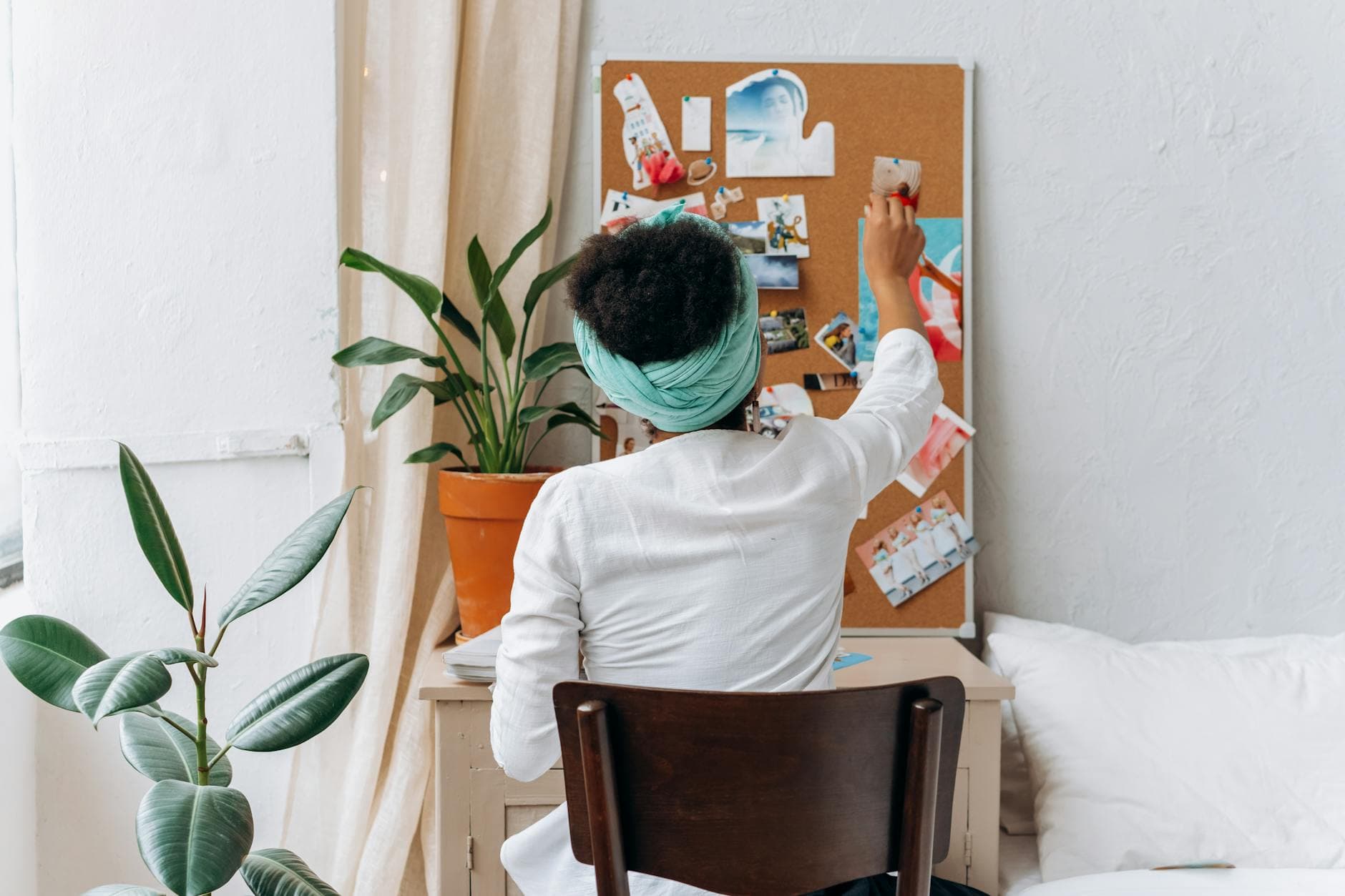 A woman in a cozy room organizing a vision board with photos and ideas. - overcome procrastination