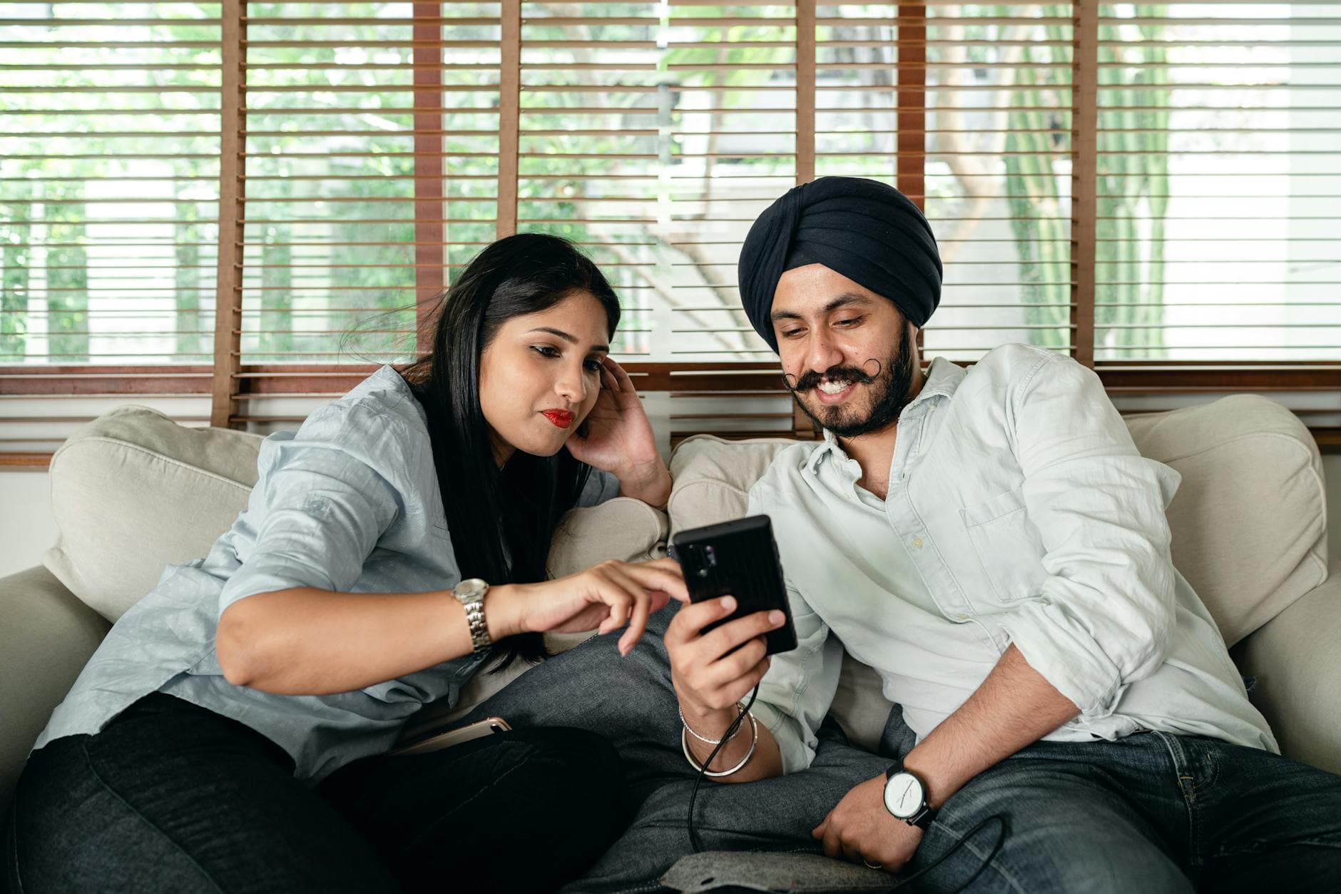 A young couple enjoying quality time at home, sharing moments on a smartphone while relaxing on the couch. - partner needs communication