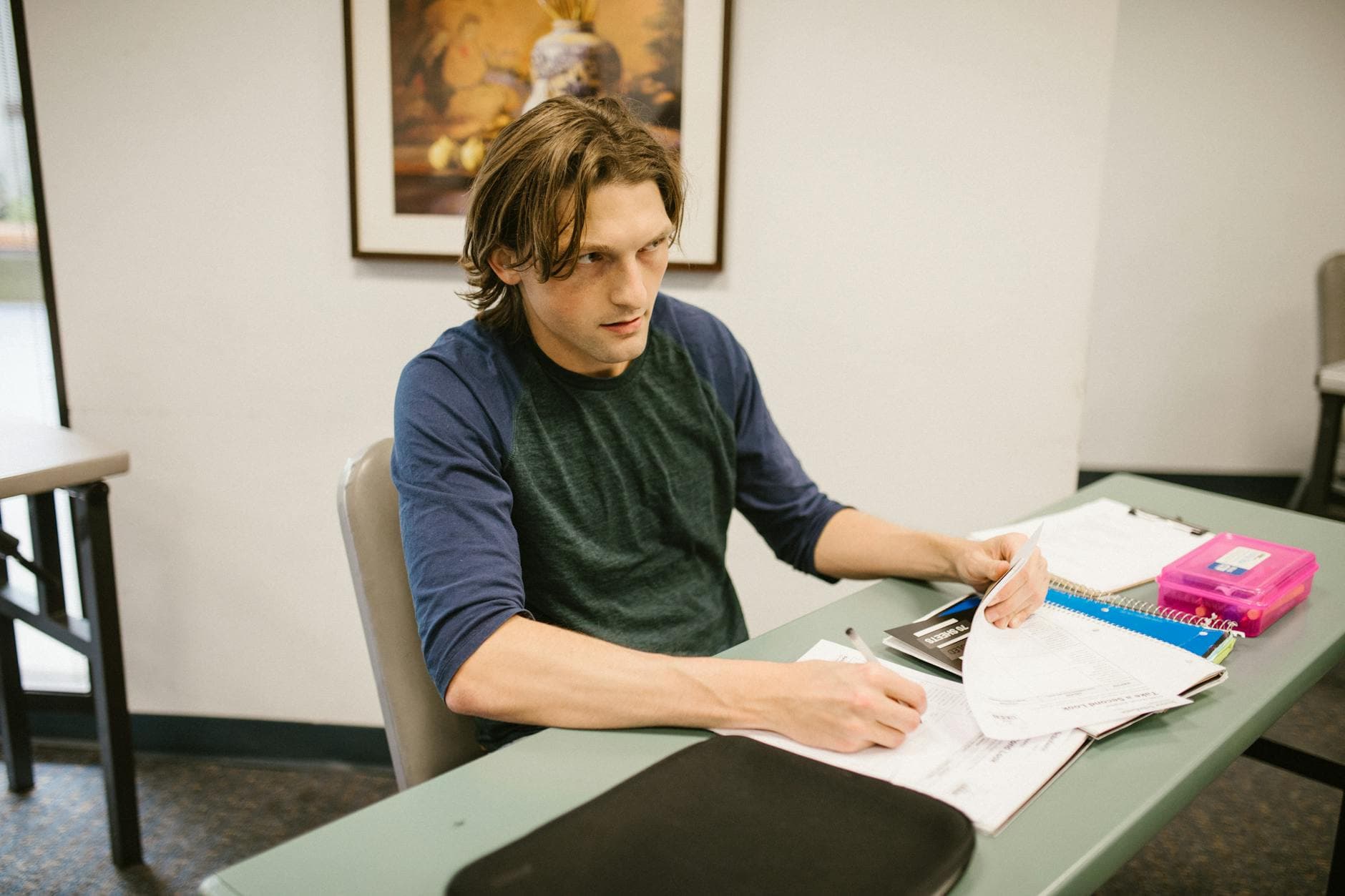 A male college student is sitting at a desk focusing on his studies in a classroom setting. - rebuilding trust cheating