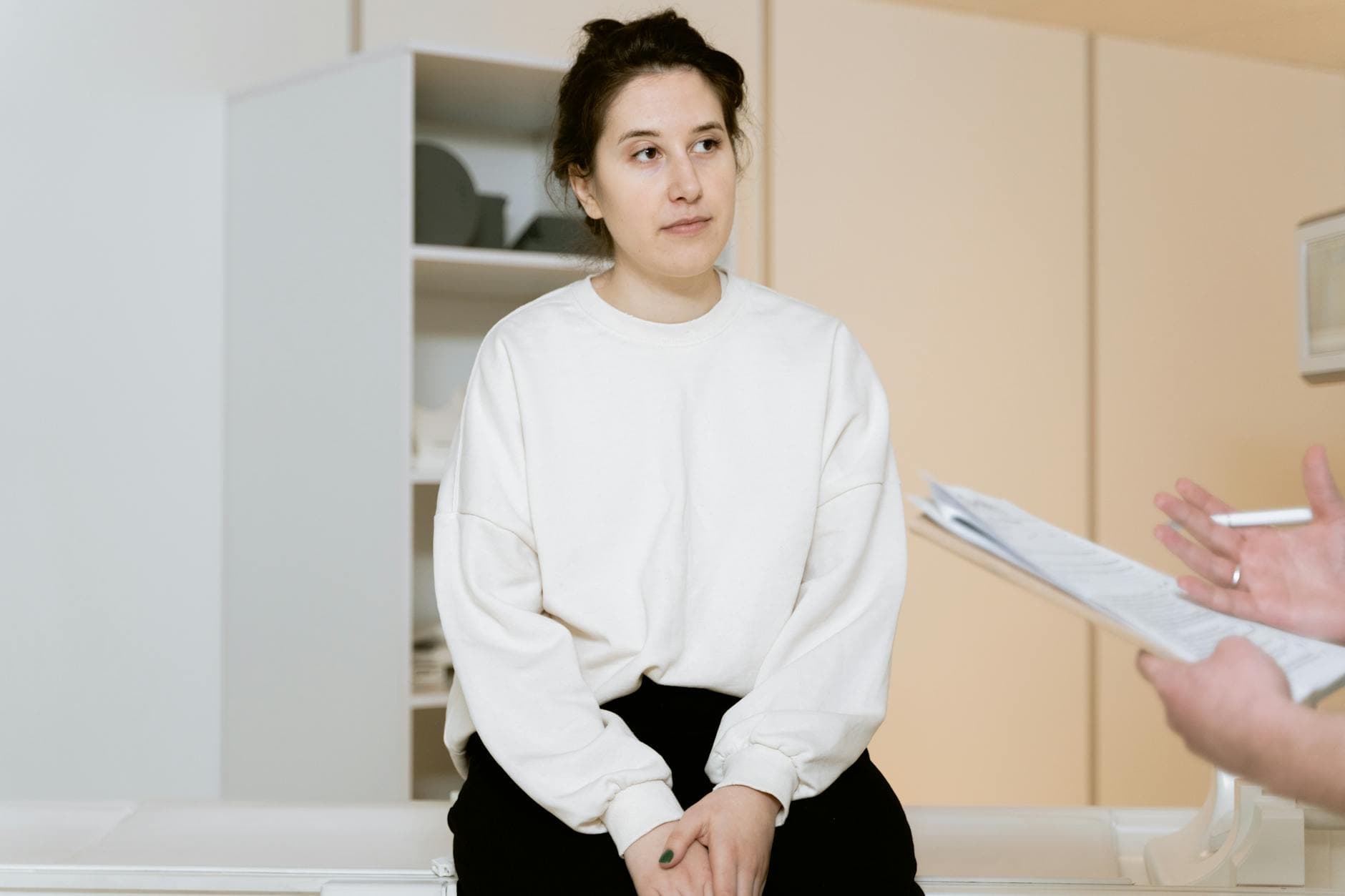 Adult woman sitting attentively during a medical consultation inside a clinic. - reddit marriage advice