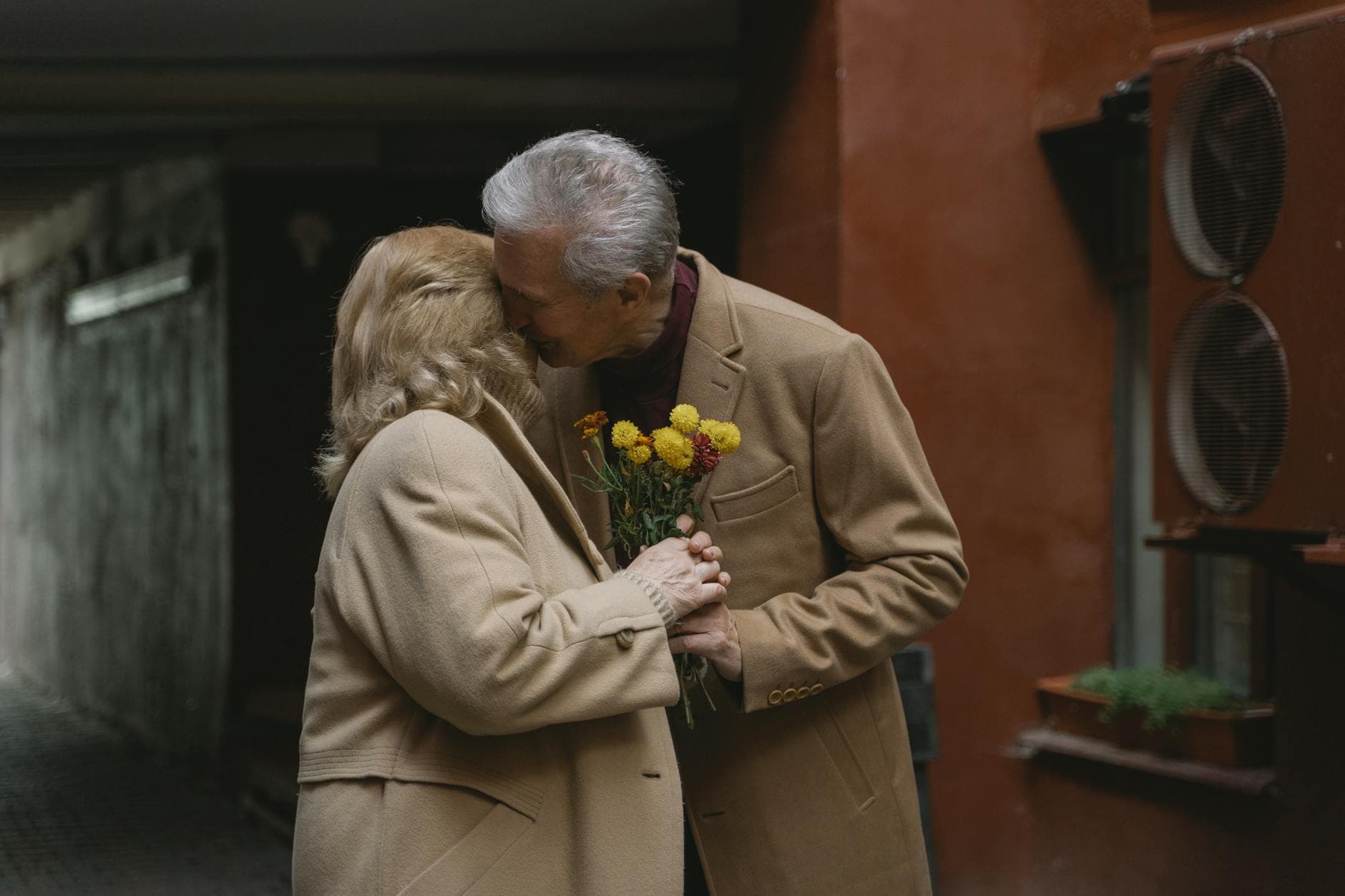 Senior couple sharing a tender moment with flowers in an outdoor courtyard. - rekindle romance