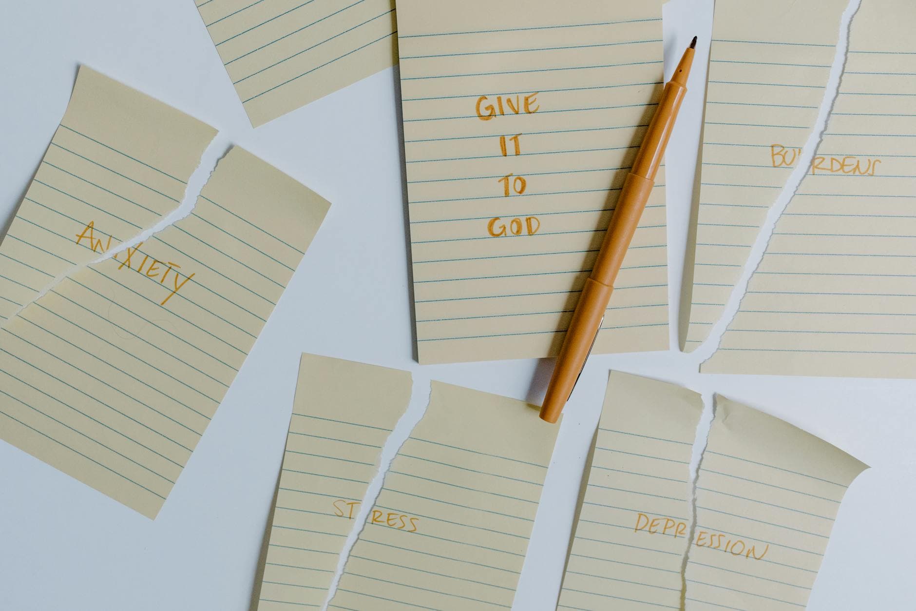 Ripped notebook pages with words anxiety, stress, depression, give it to God and a pen on a table. - relationship anxiety spring