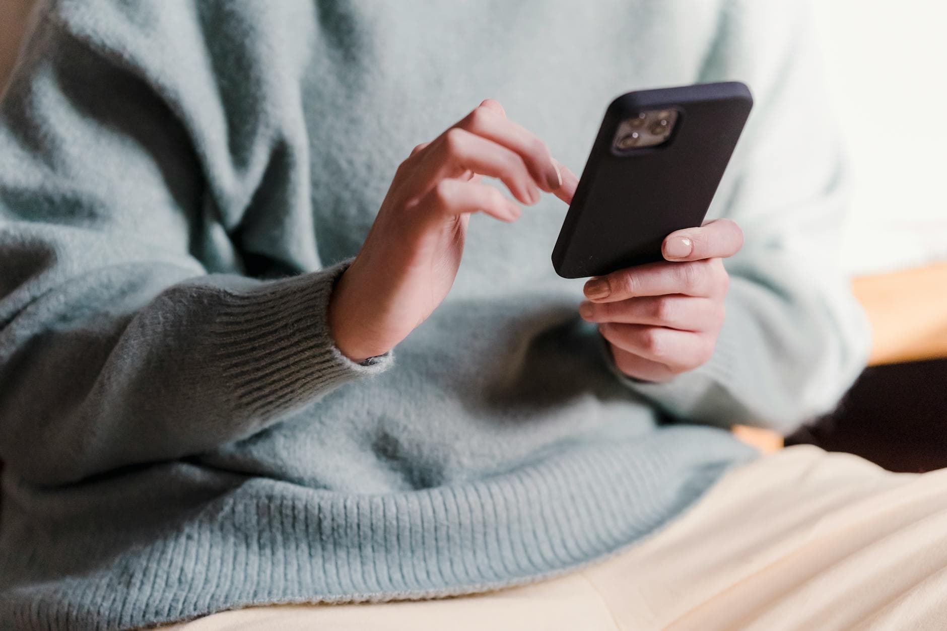 Crop faceless female in casual clothes using smartphone and touching screen while chilling at home - relationship communication check-in