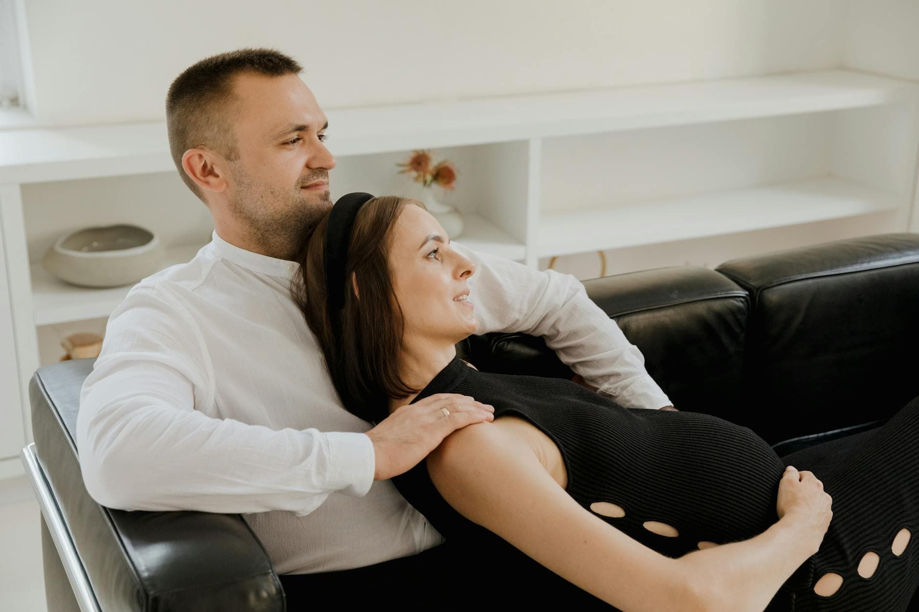 A loving expectant couple sits on a sofa, enjoying a peaceful moment together. - reset relationship expectations