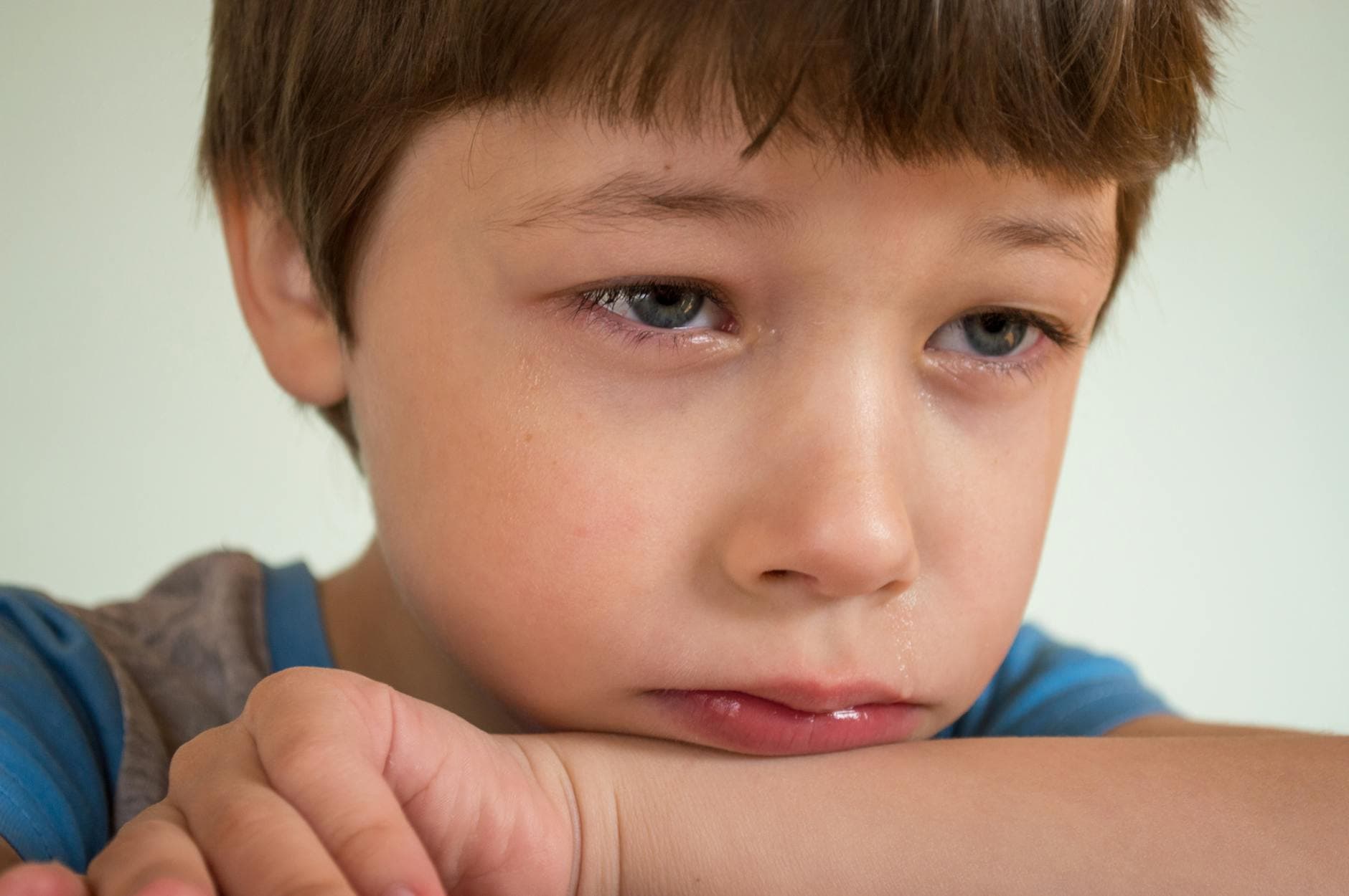 Close-up of a young boy looking sad and contemplative. - sad cbt treatment