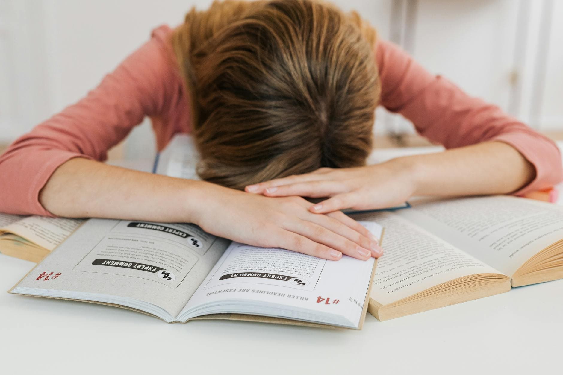 A student overwhelmed by studying falls asleep on open books at a desk, representing academic fatigue. - school break transition