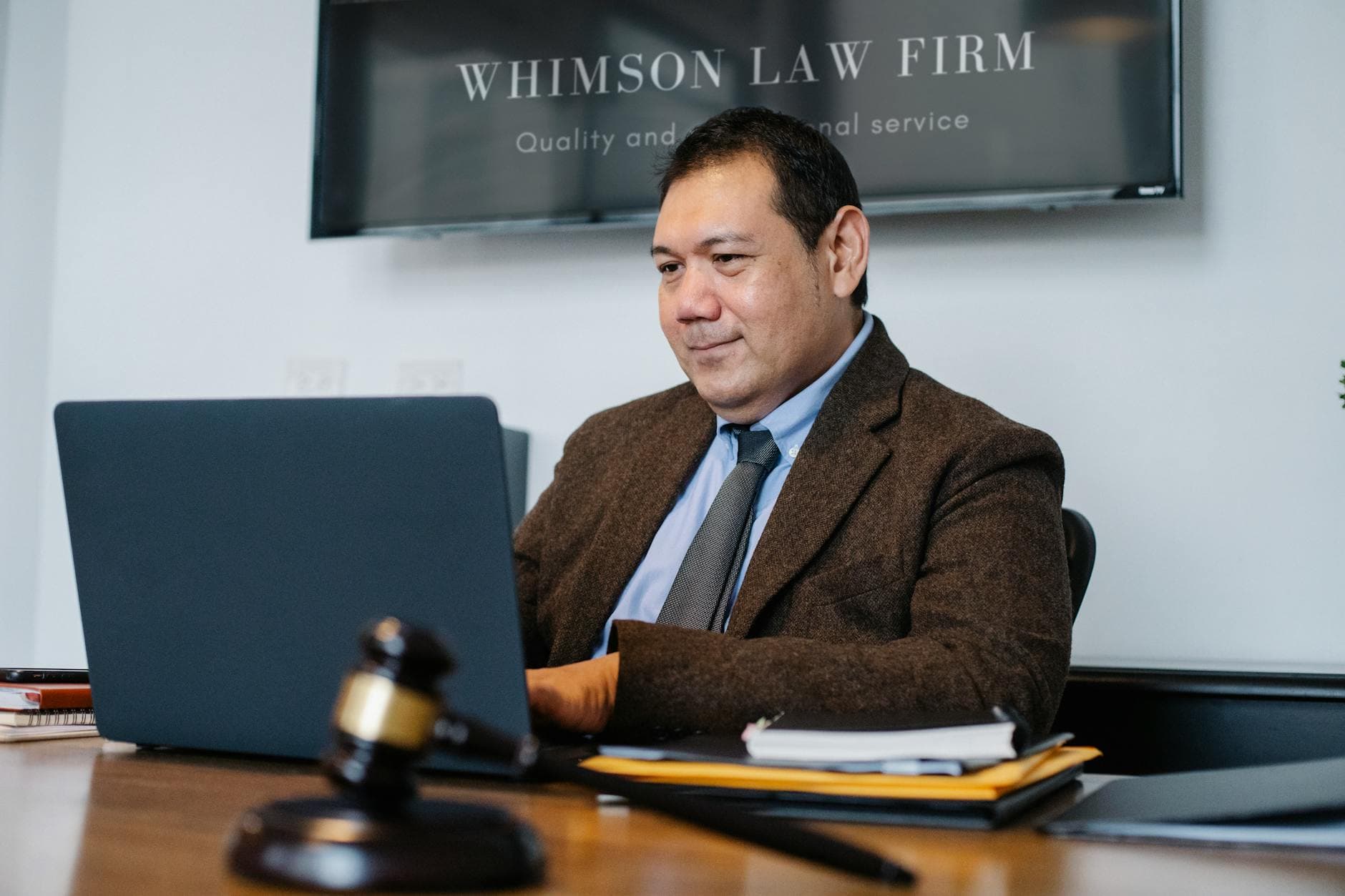 A lawyer working on a laptop in a legal office, wearing a suit and tie, with a gavel on the desk. - sexless marriage advice