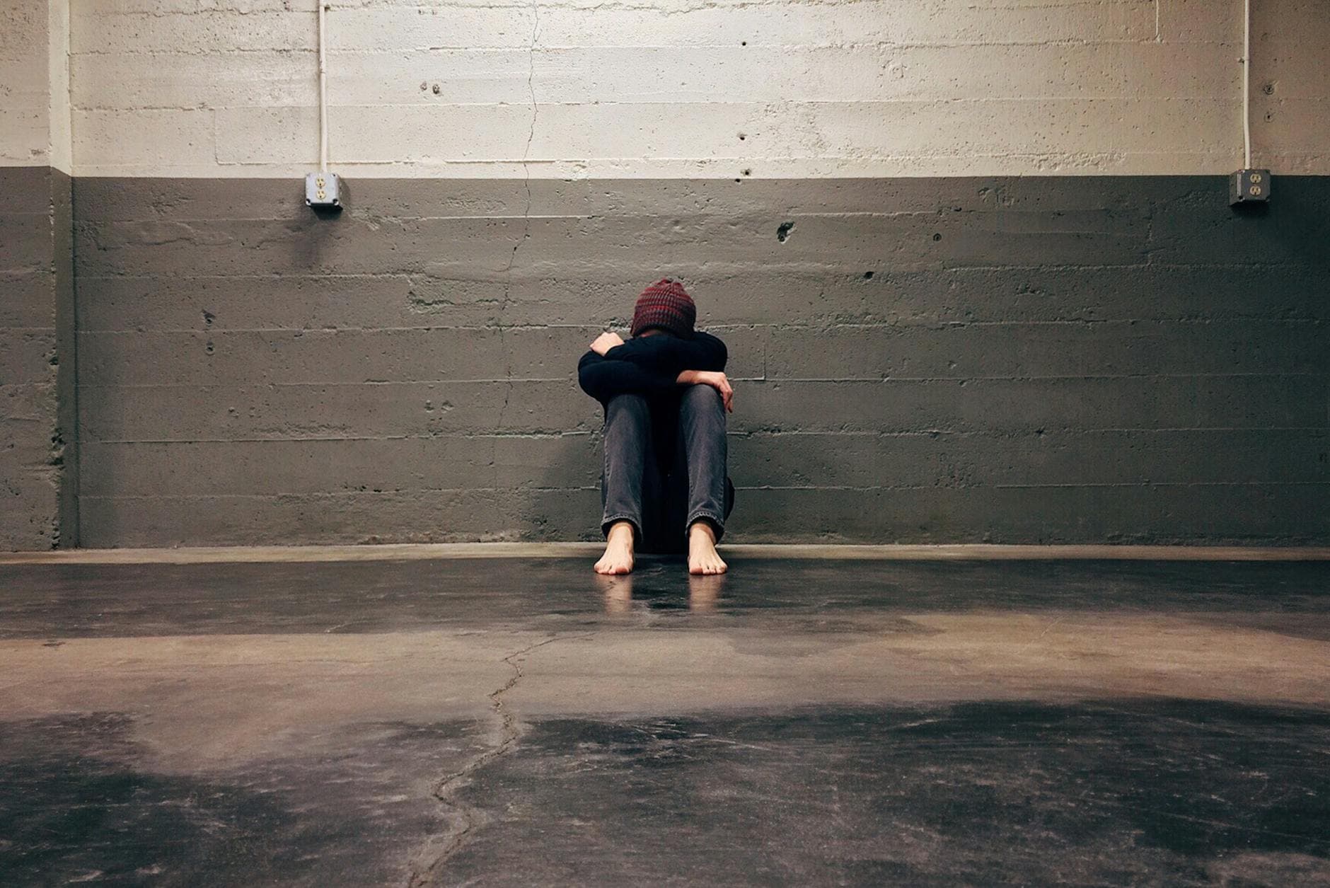 A person sitting alone in a corner, evoking themes of solitude and emotion. - social media mental health