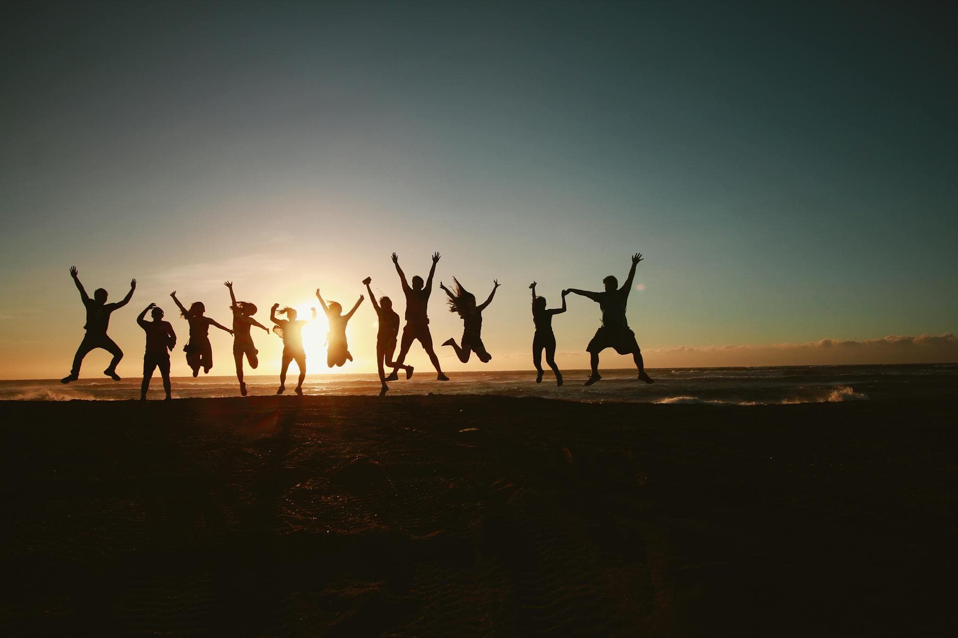 Silhouette of a group of friends jumping on a beach at sunset, expressing joy and freedom. - spring break family boundaries