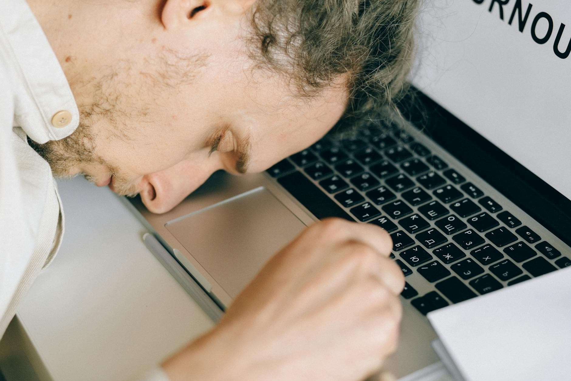 Exhausted employee resting head on laptop keyboard due to burnout and stress. - spring fatigue causes