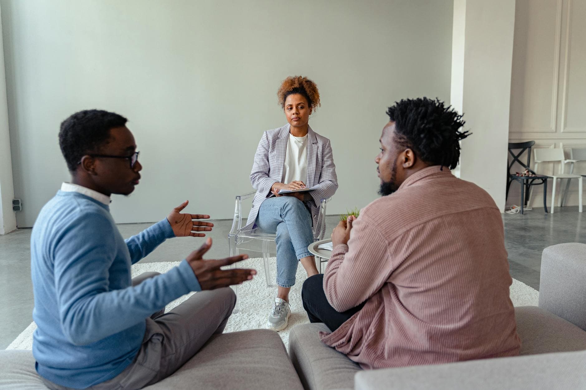 A therapist mediates a session with two men on a couch discussing mental health. - spring mental reset