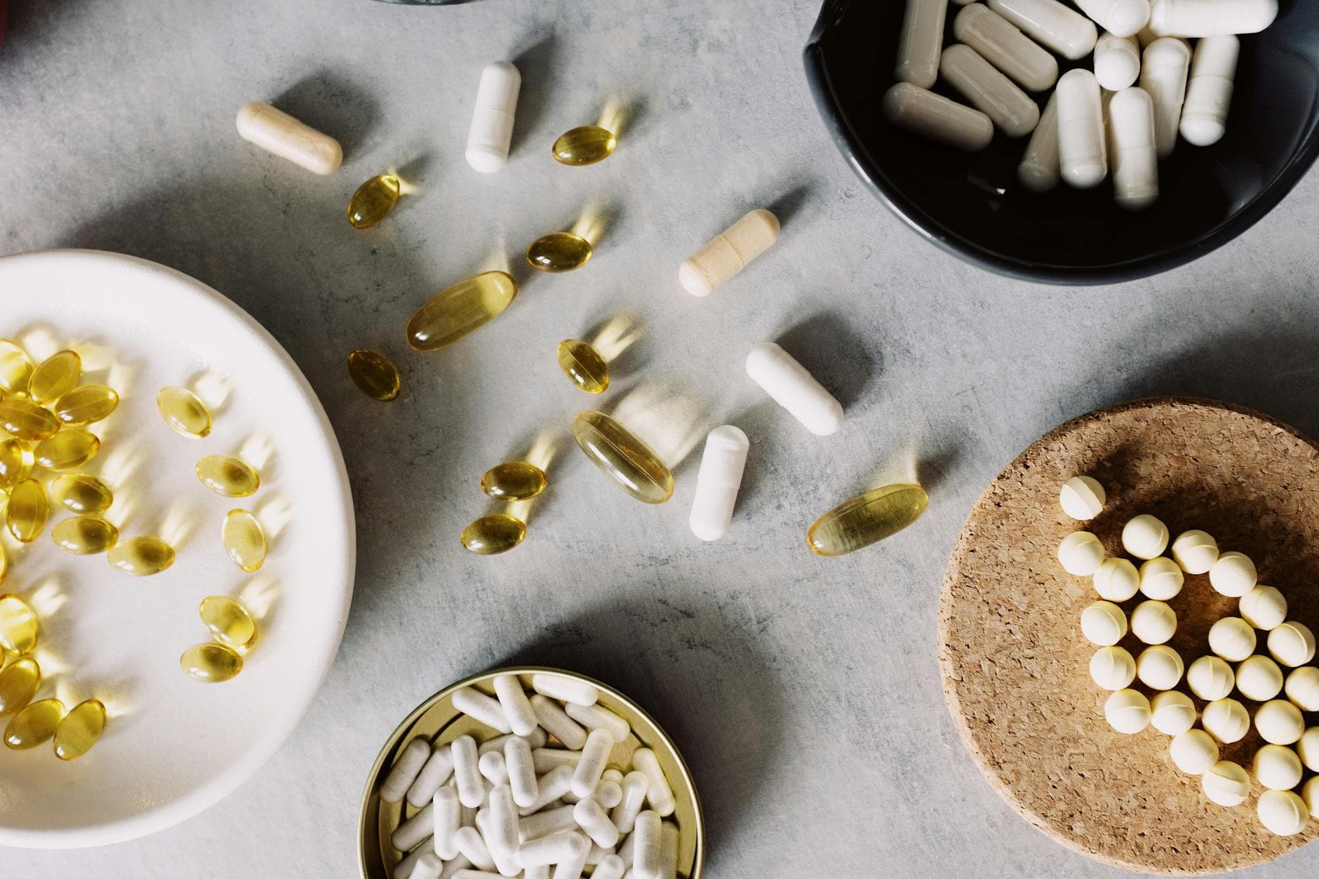 A variety of pills and capsules arranged on a grey surface, showcasing health and wellness. - spring slump remedies