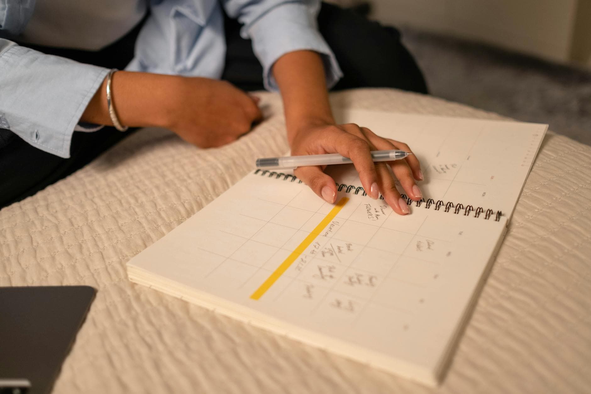 Close-up of a person scheduling in a spiral-bound planner using a pen. Indoor setting. - therapy intentions
