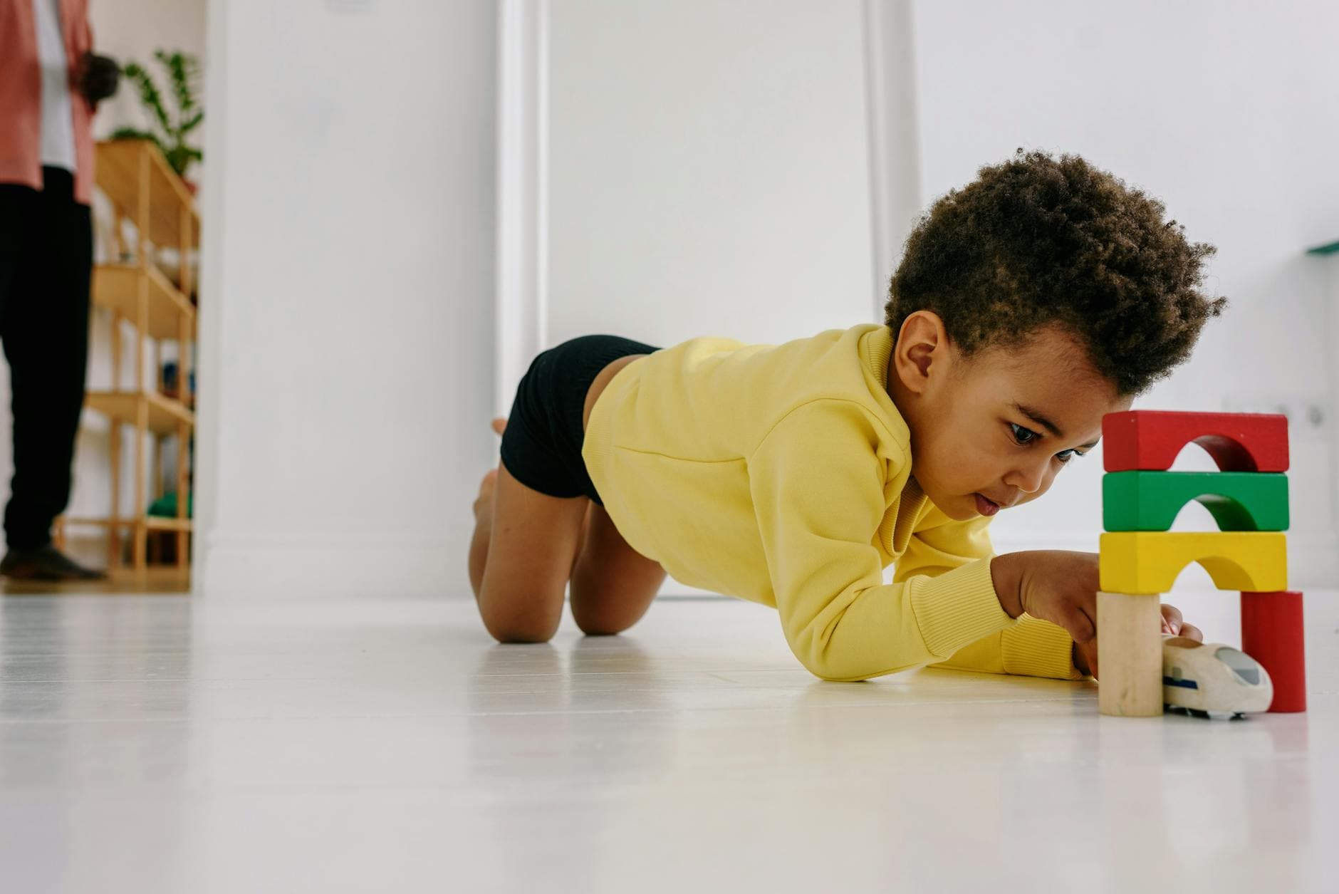 Young child engaged with toy blocks in a bright home setting, expressing creativity and fun. - toddler playdate skills