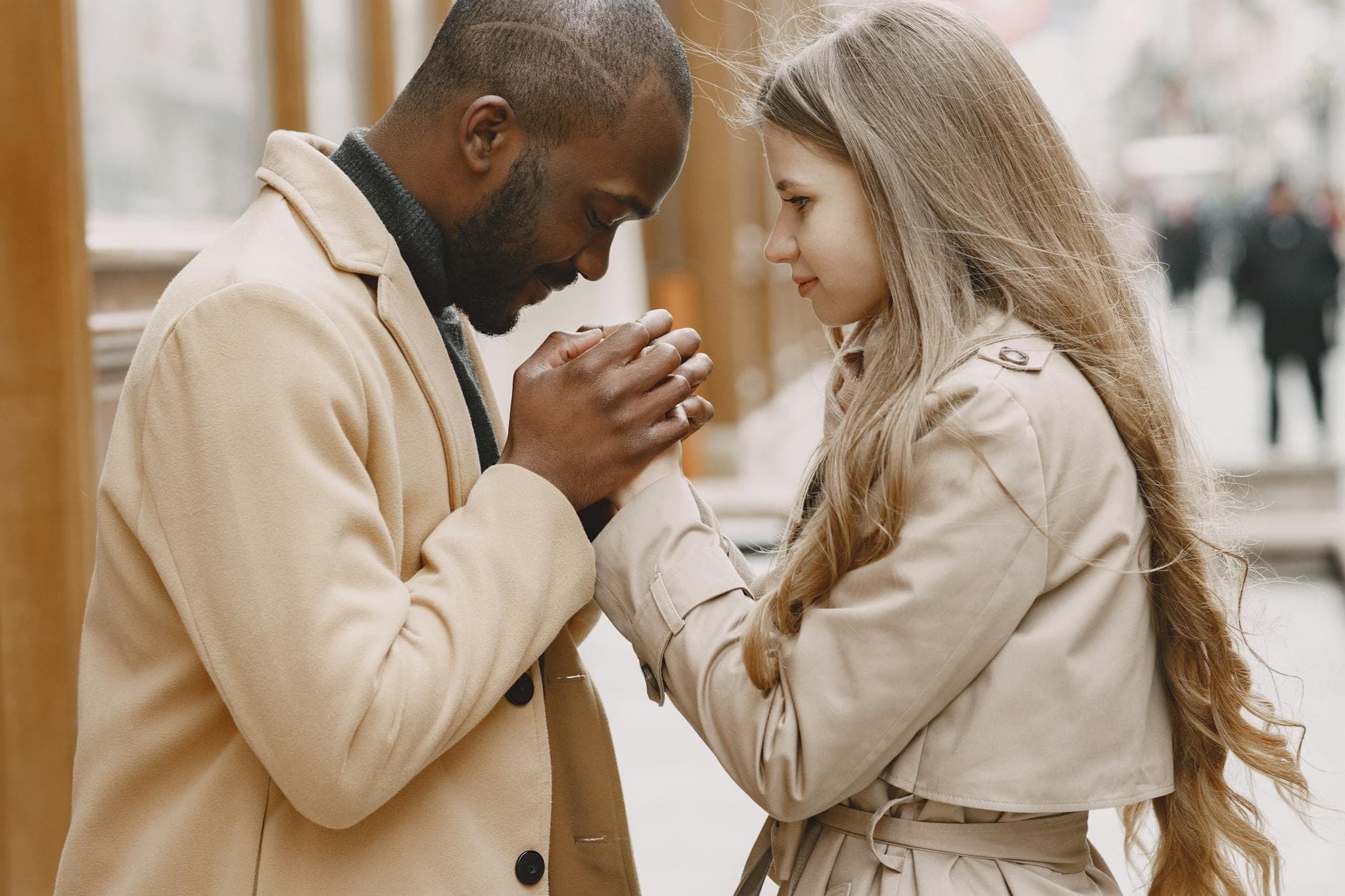 A multiracial couple in winter clothing sharing an intimate moment outdoors. - what does apologize mean
