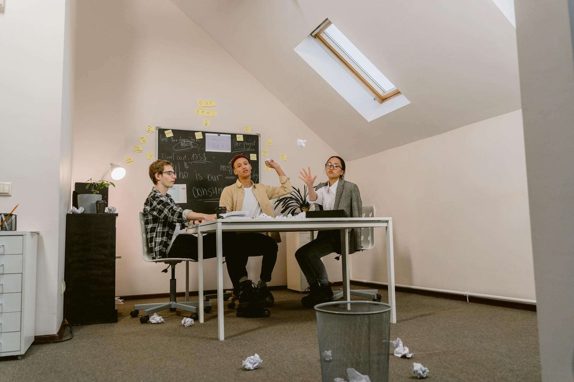 Young professionals brainstorming in an office, throwing crumpled papers playfully around. - declutter communication