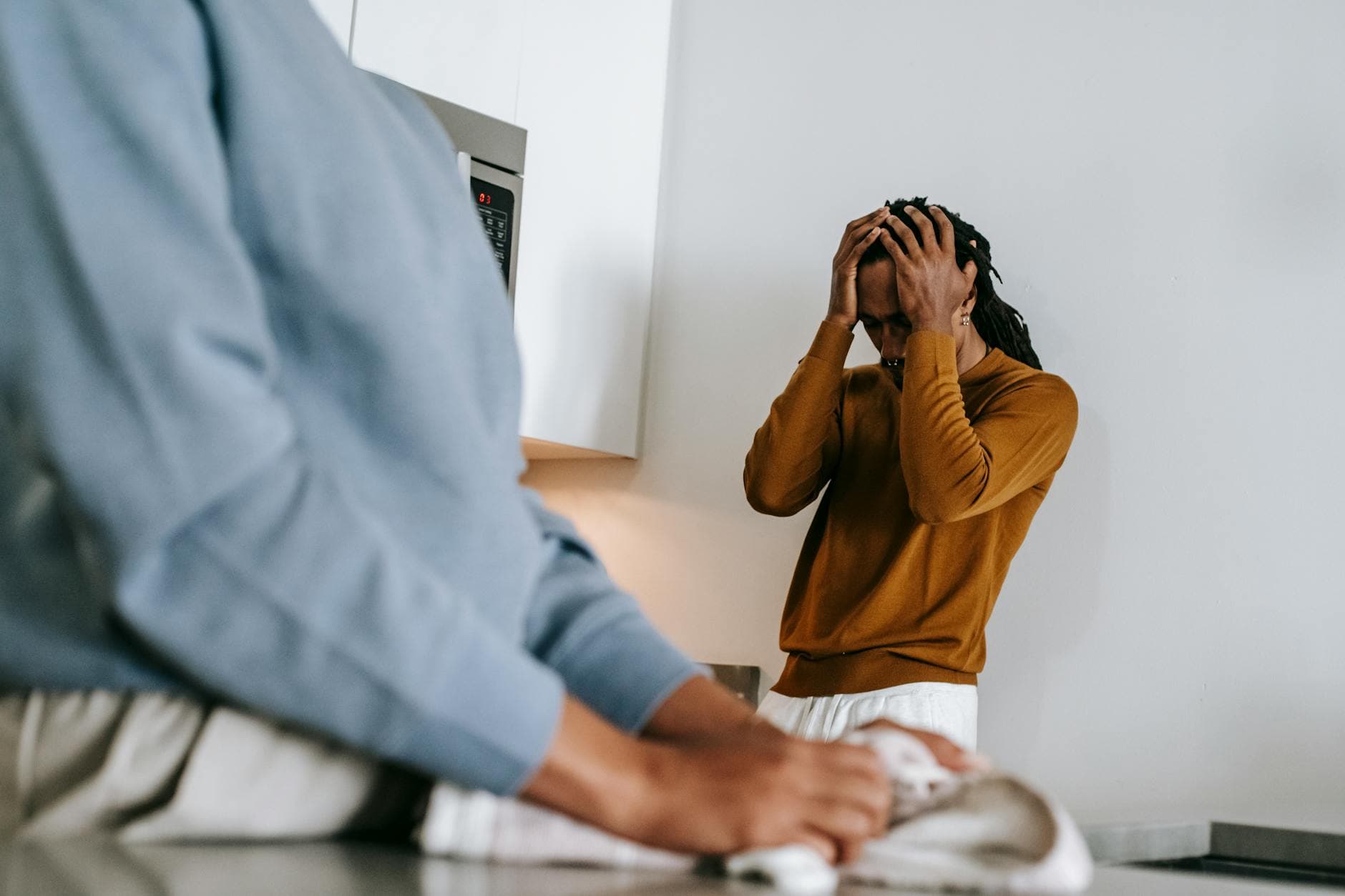 Black man and faceless woman arguing while standing in kitchen and wearing casual clothes in daytime - declutter relationship conflict
