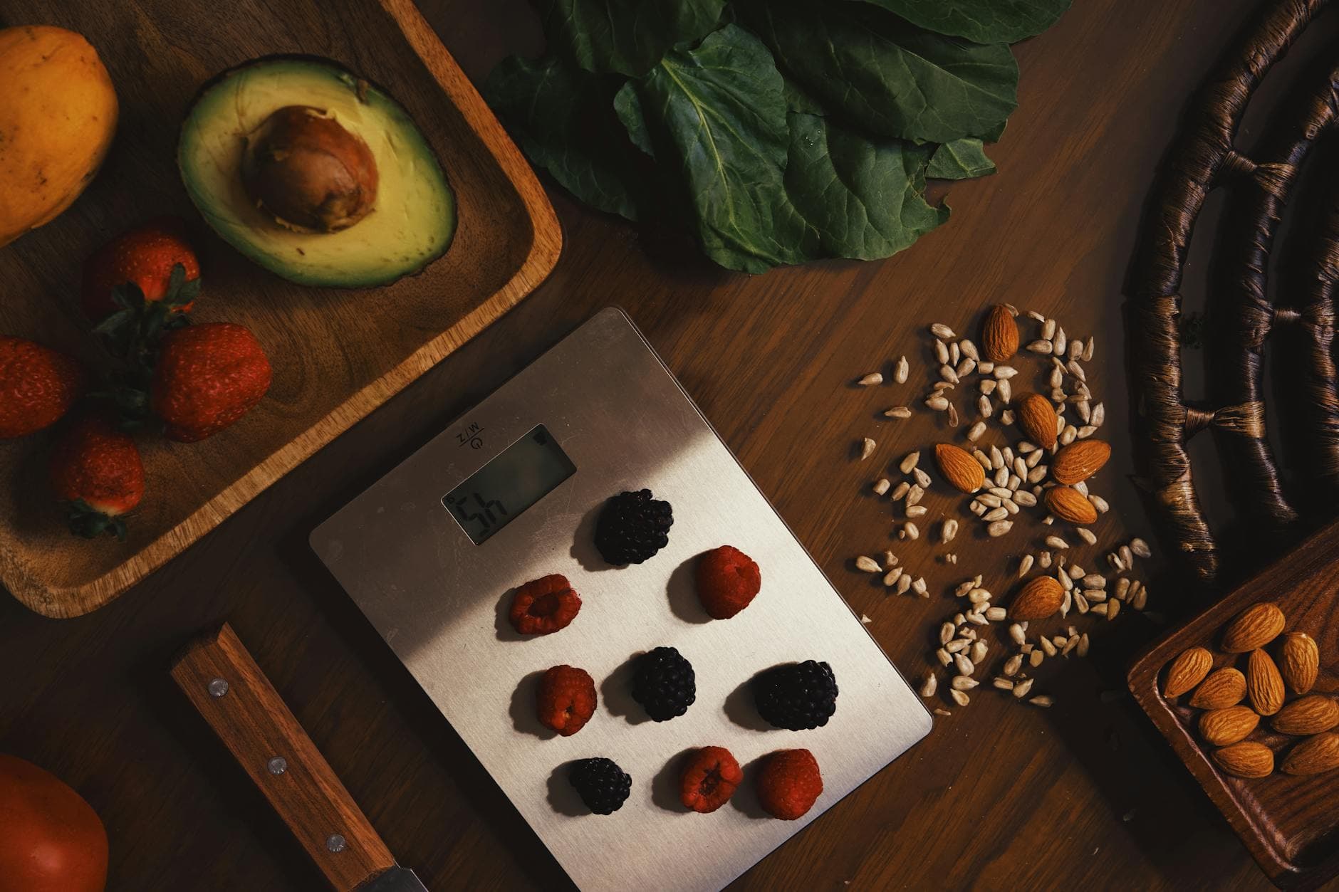 Top view of composed raw almond with seeds and avocado on table with berries on scales for cooking healthy dish - diet for mental clarity