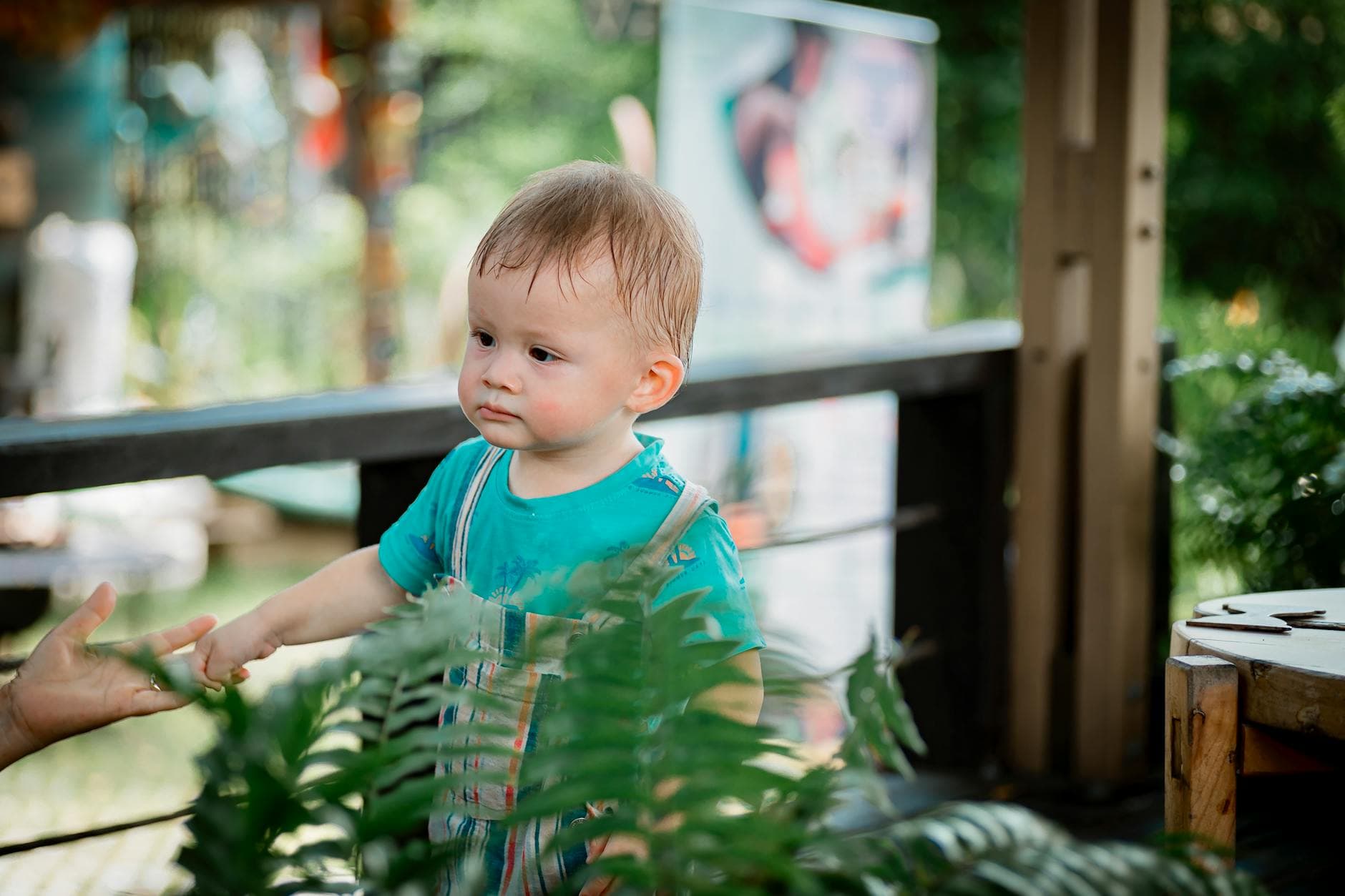 Cute toddler enjoys outdoor adventure surrounded by green plants. - independent play toddler