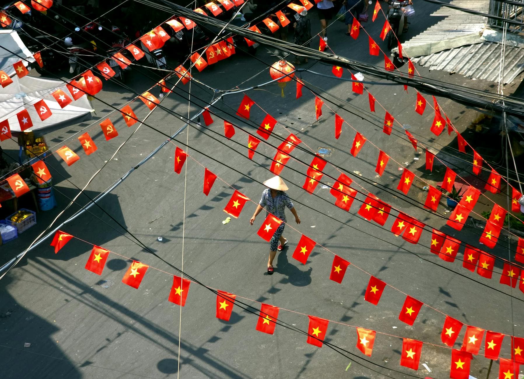 A street view with Vietnamese flags and a person in a conical hat, captured from above. - red flags relationships