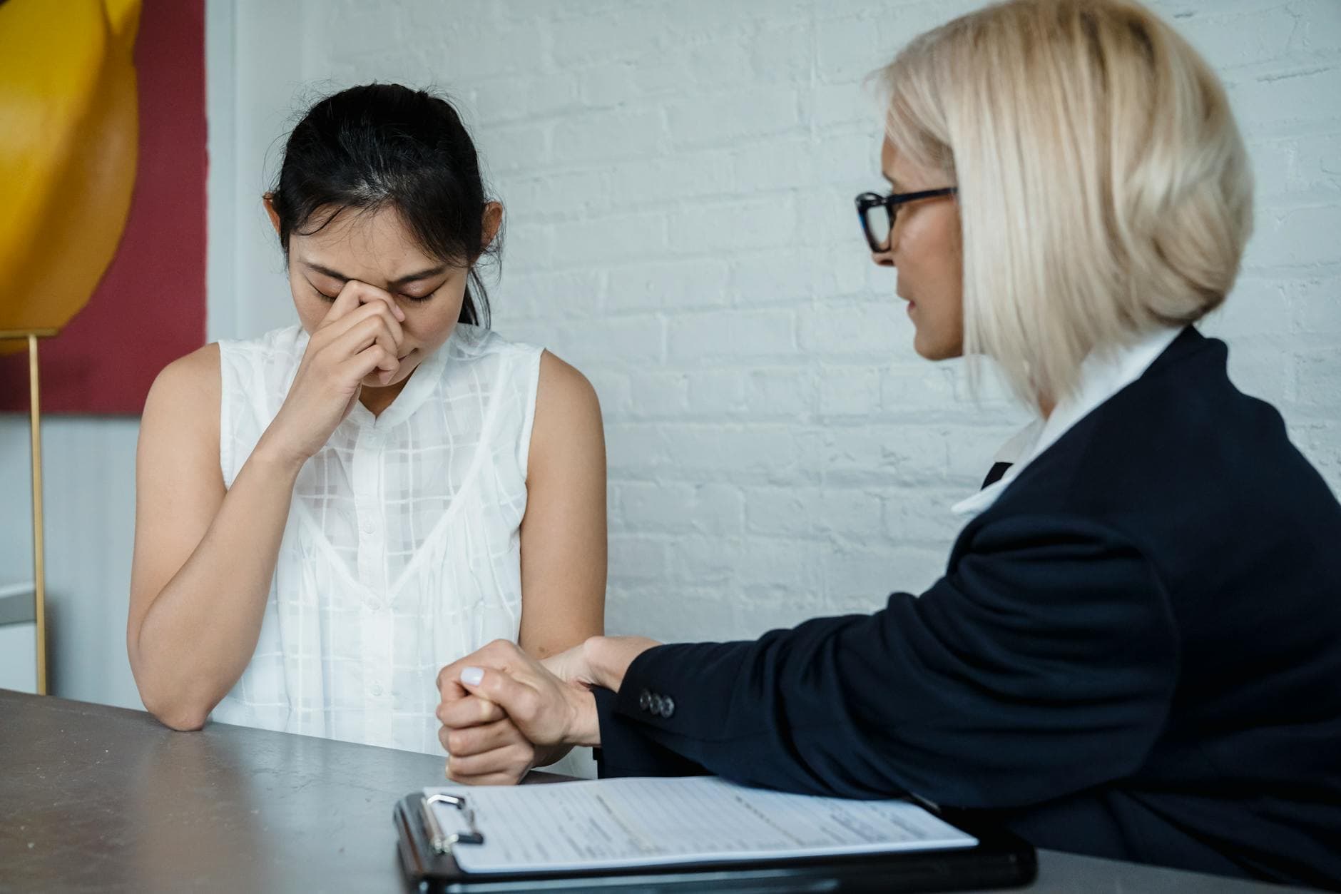 Emotional therapy session featuring a supportive female therapist helping a worried young woman. - sad therapist