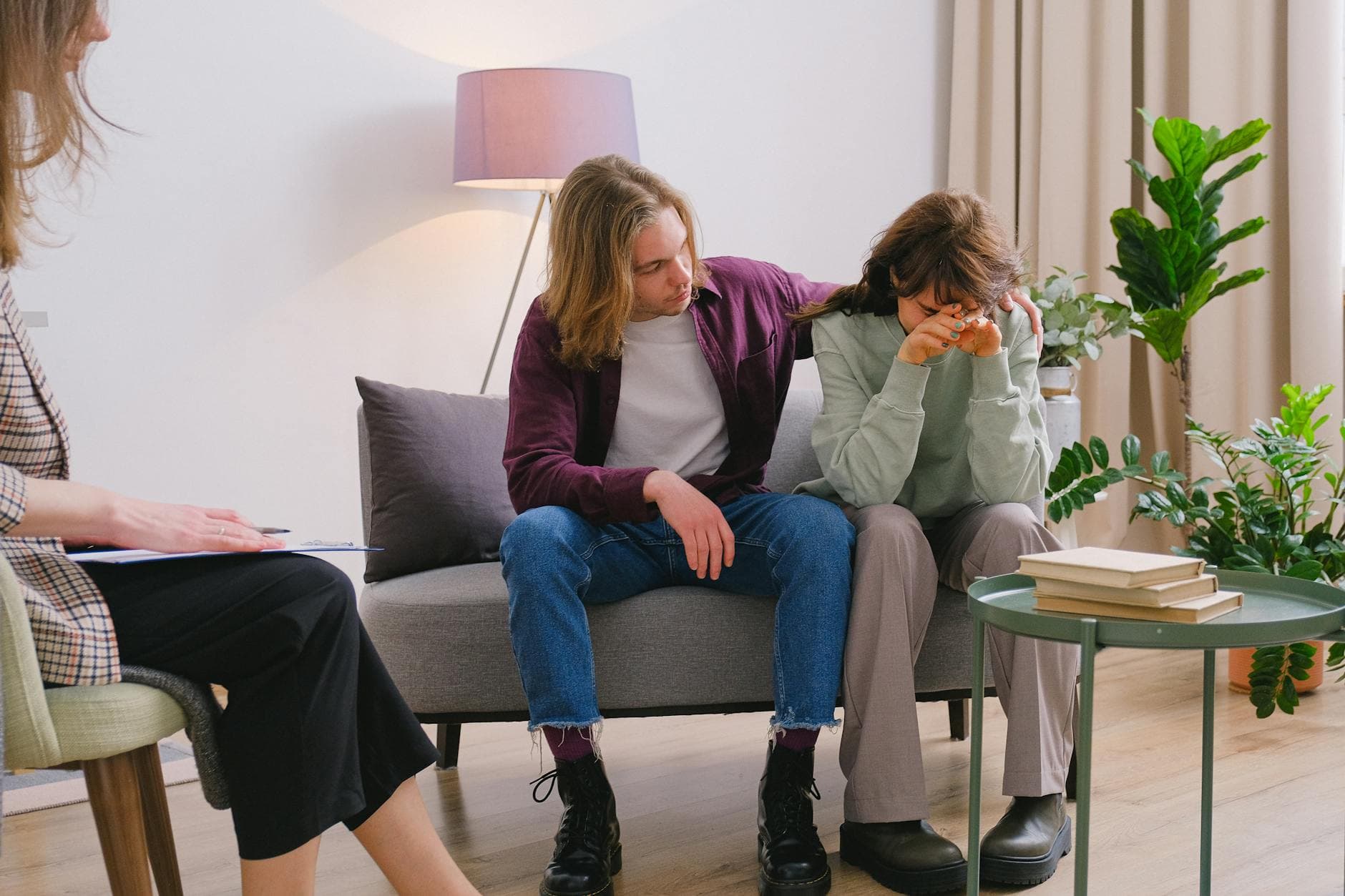 Young male embracing frustrated girlfriend during session with psychologist in light room in daytime - sad treatment options