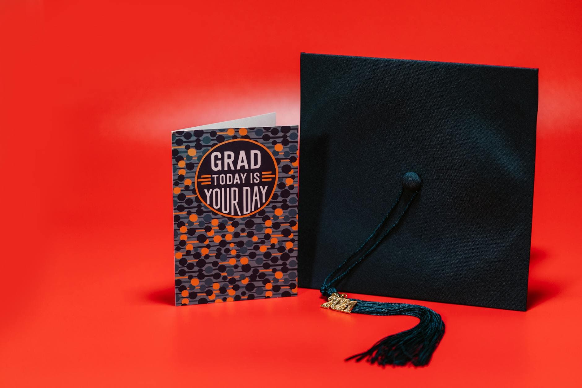 Graduation cap and card against a bold red background, celebrating achievement. - post grad adjustment
