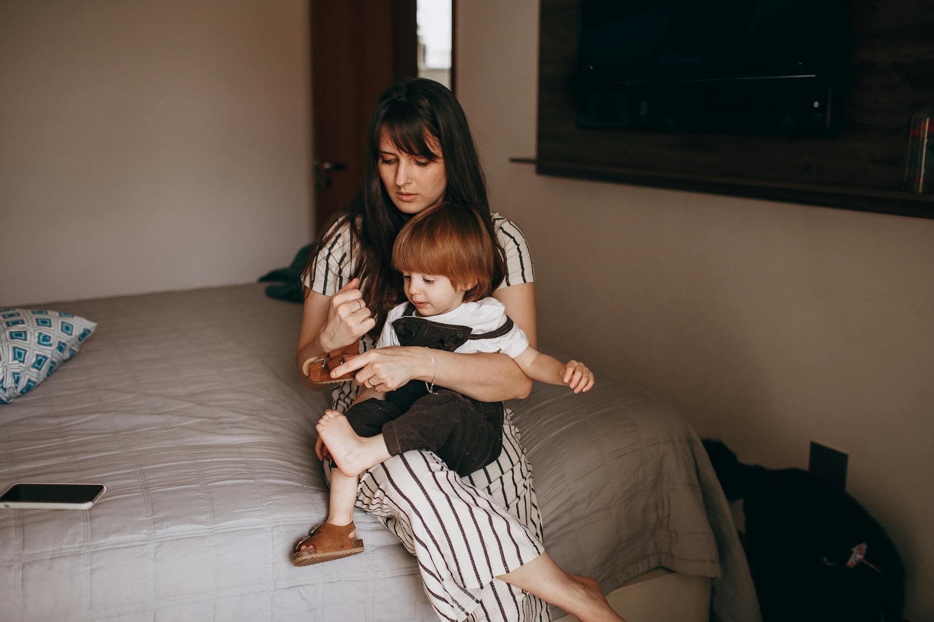 A mother and child sitting on a bed, sharing a quiet moment together indoors. - toddler personal space