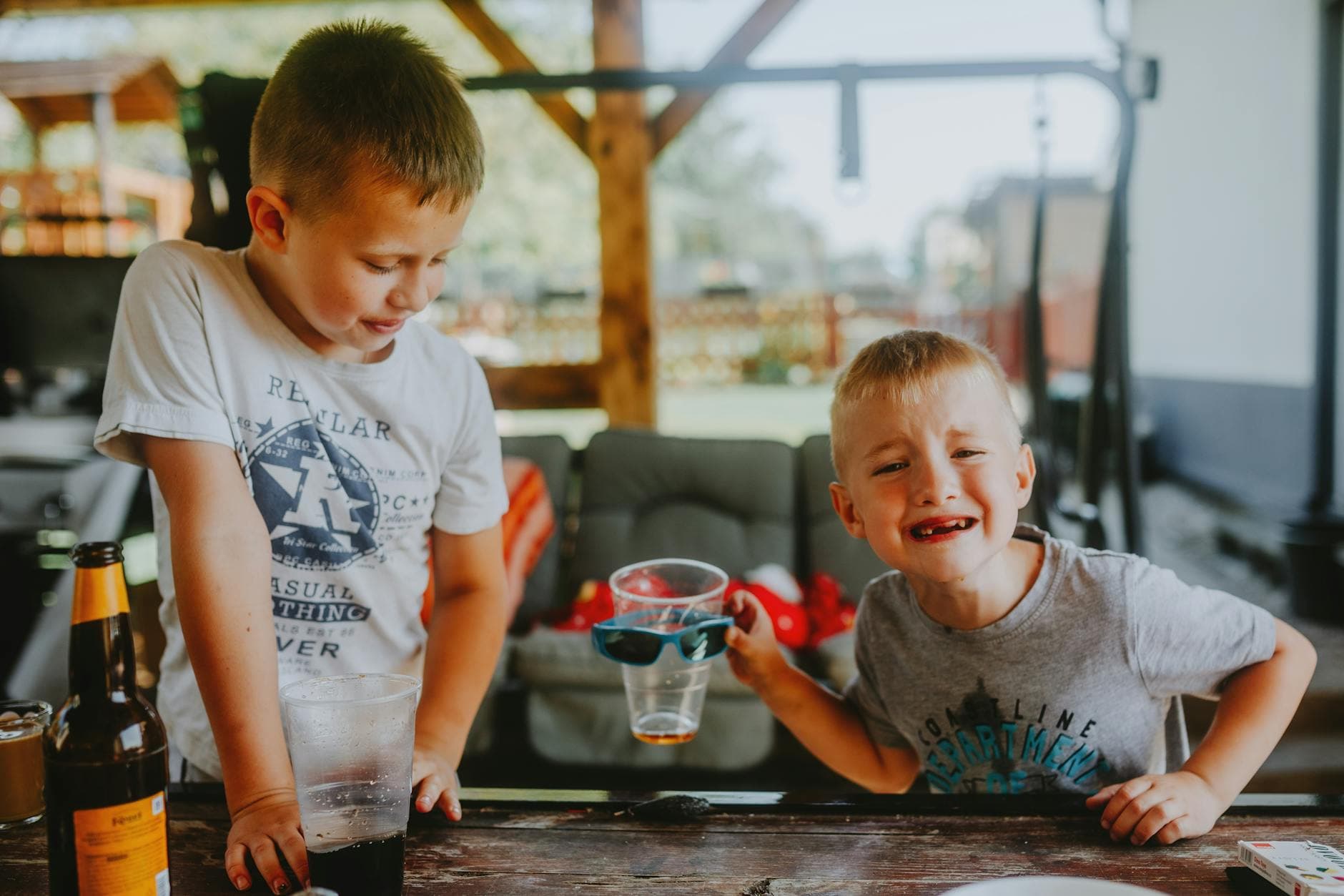 Two young boys having fun outdoors with drinks and laughter. - toddler sharing