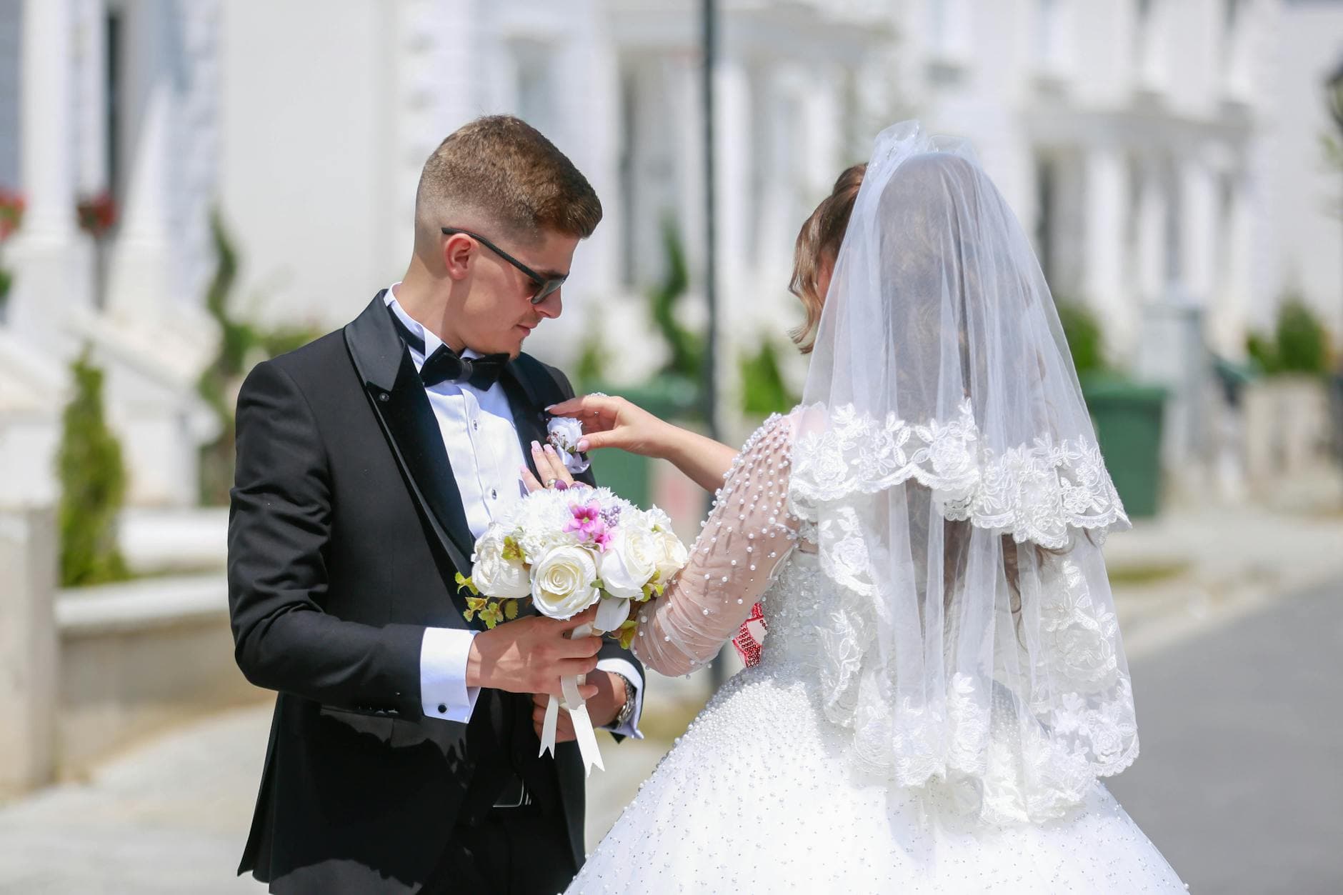 A bride and groom share a moment outdoors on their wedding day, holding a bouquet and dressed in formal attire. - wedding day anxiety