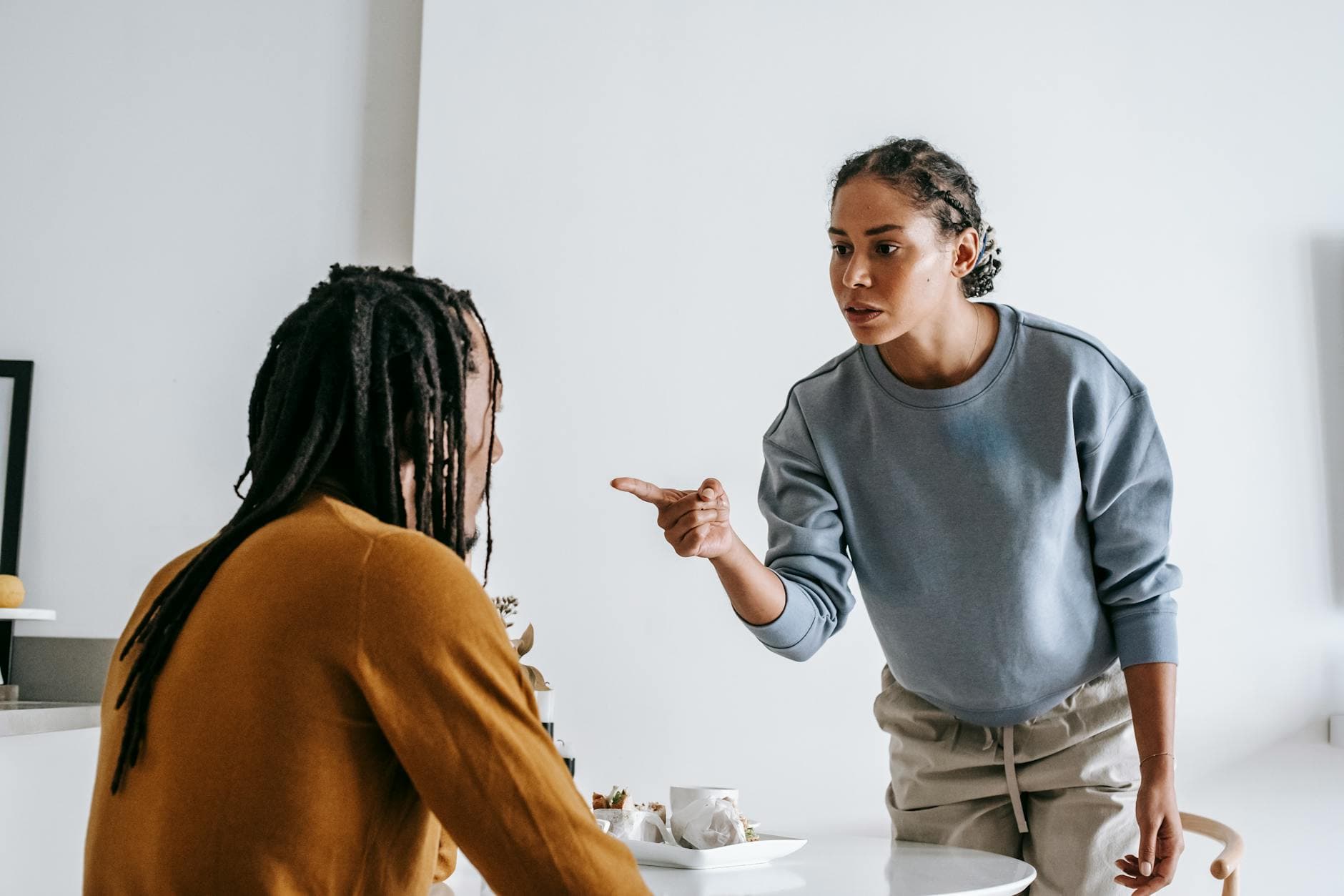 Young African American female standing near table while male sitting at kitchen and having argument - effective relationship communication skills