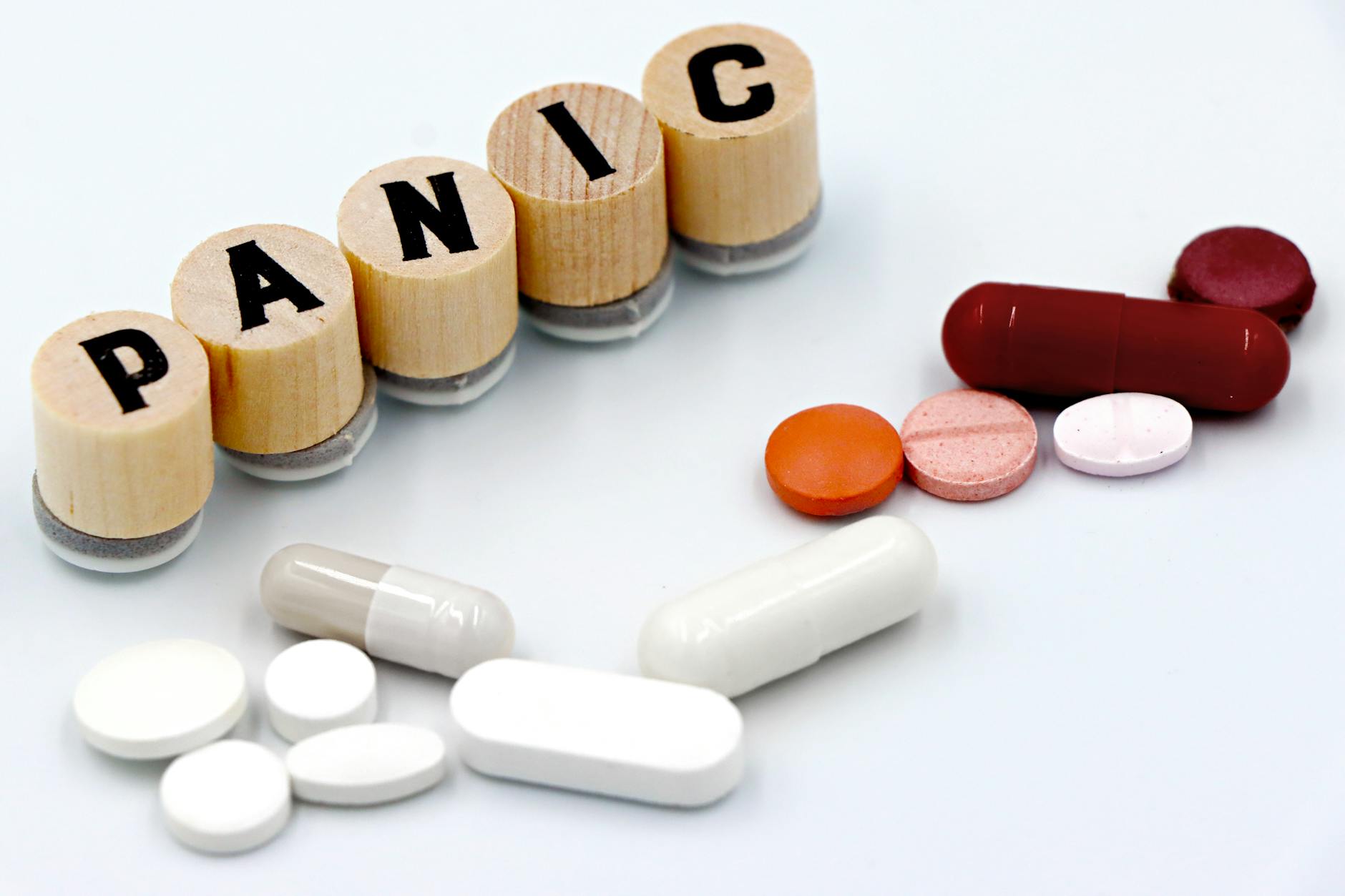 Assorted pills arranged beside wooden tiles spelling 'PANIC', symbolizing anxiety treatment. - anxiety and depression treatment