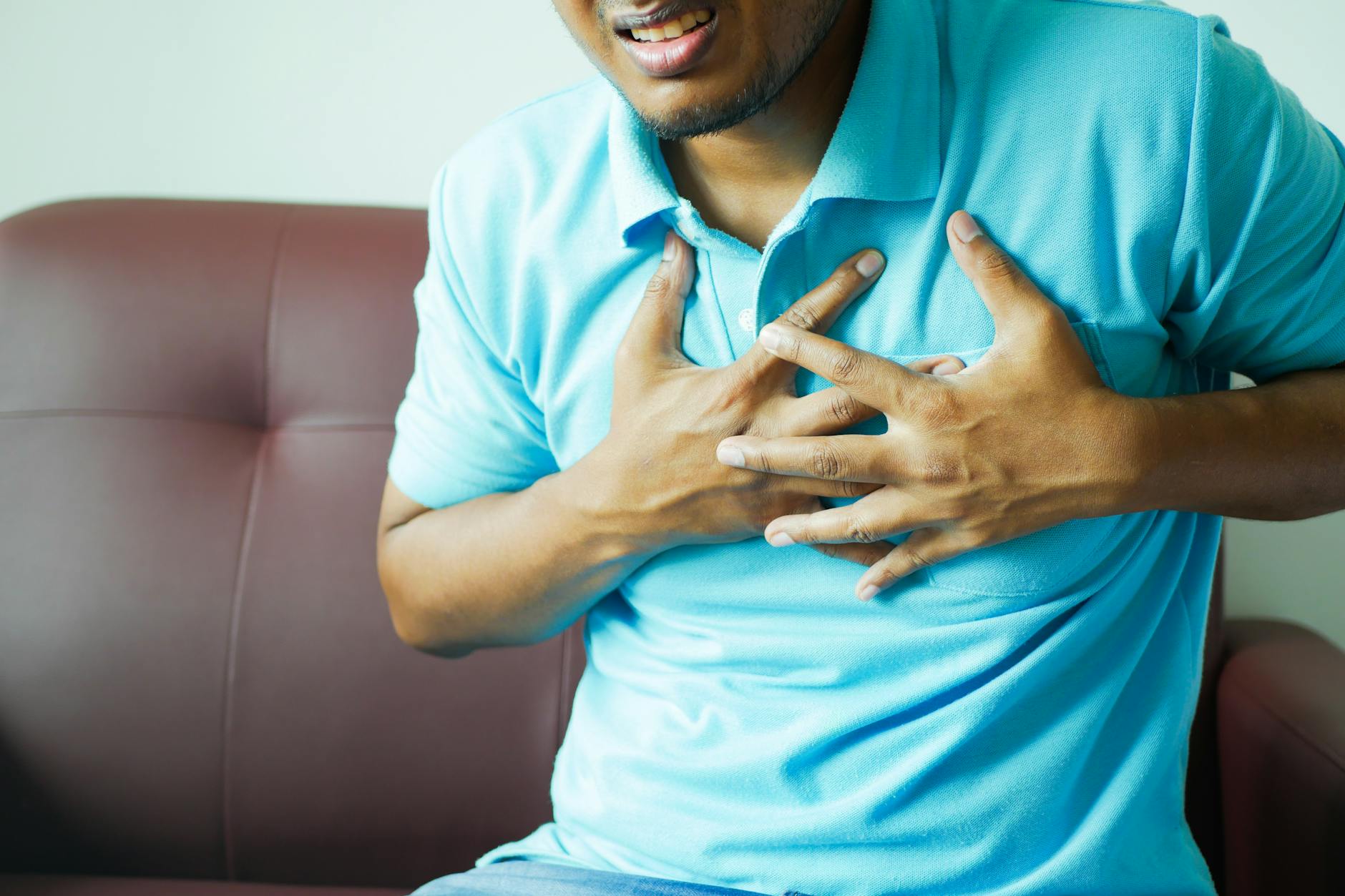 A close-up image of a man clutching his chest, indicating heart pain or discomfort. - anxiety symptom checklist