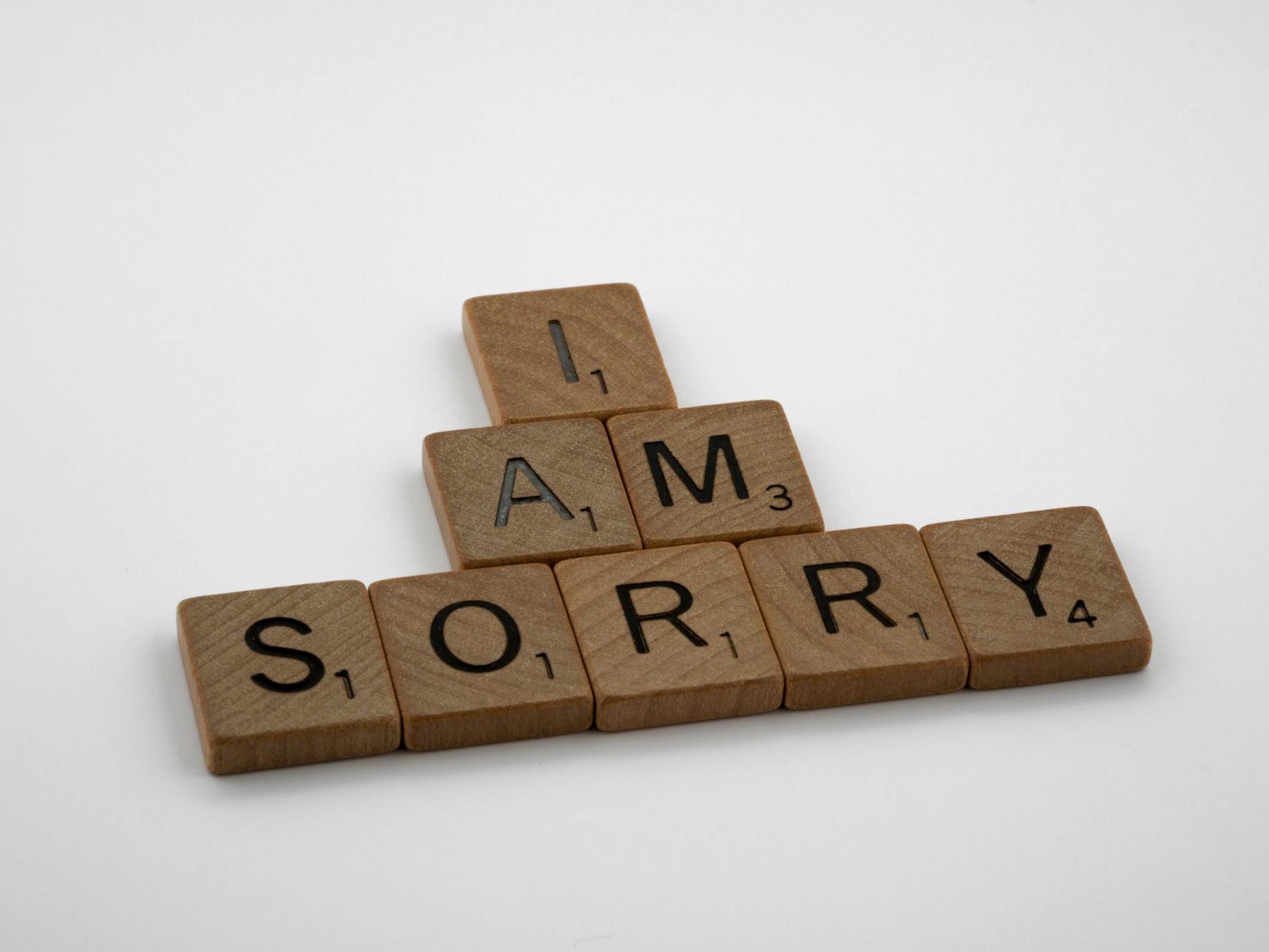 Wooden Scrabble tiles arranged to say 'I Am Sorry' on a clean white background, conveying a message of apology. - apologize to a friend