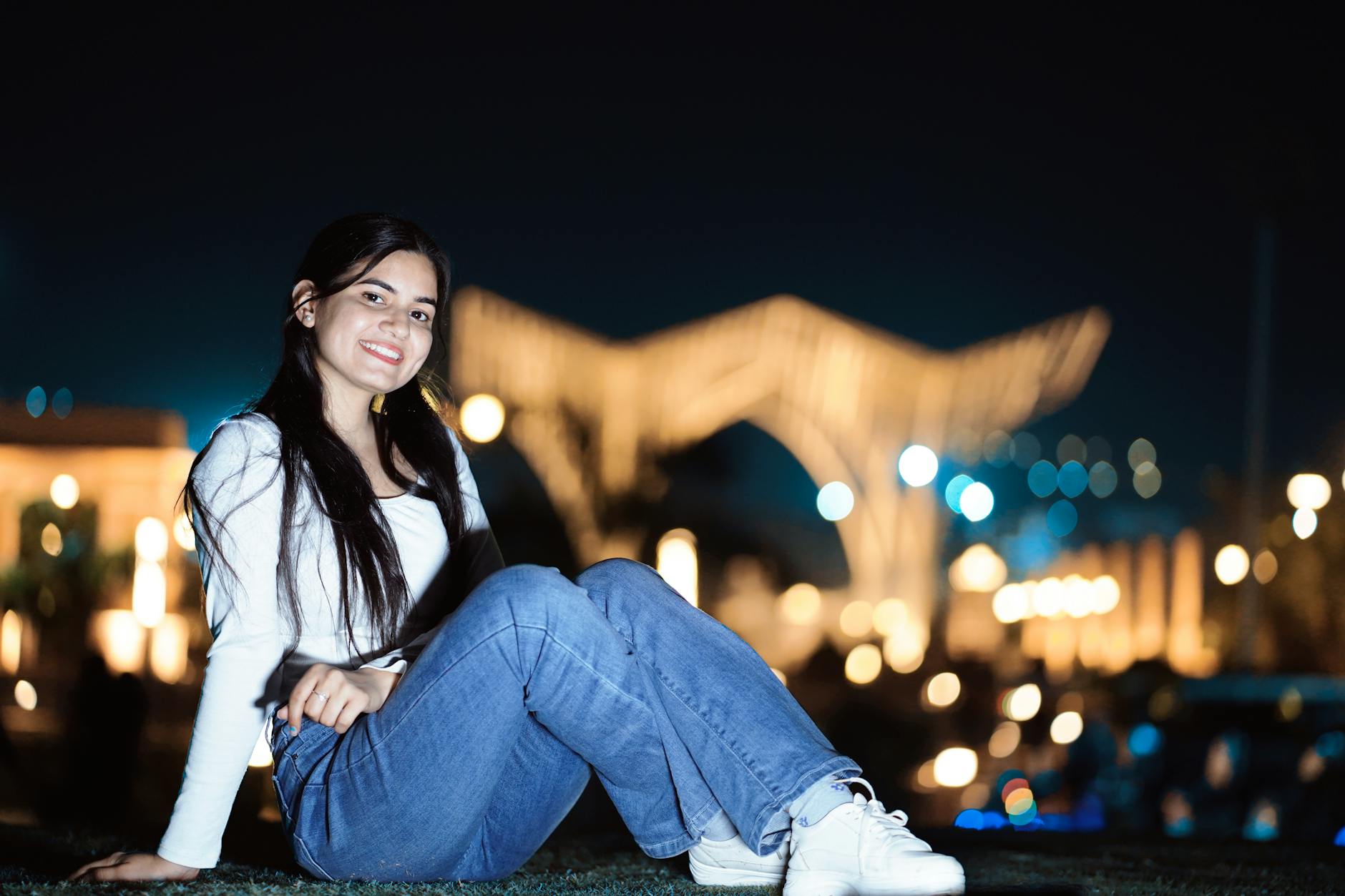 Young woman posing with a smile in an outdoor nighttime setting with blurred lights. - how to apologize for hurting someone