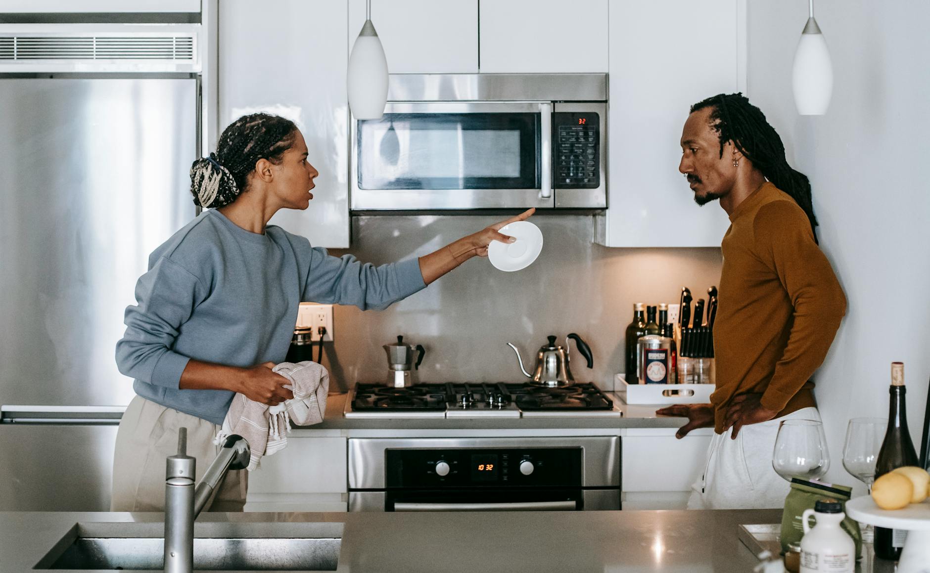 Side view of young displeased ethnic female pointing at serious male partner with hand on hip while looking at each other during conflict - cbt for winter negative self-talk