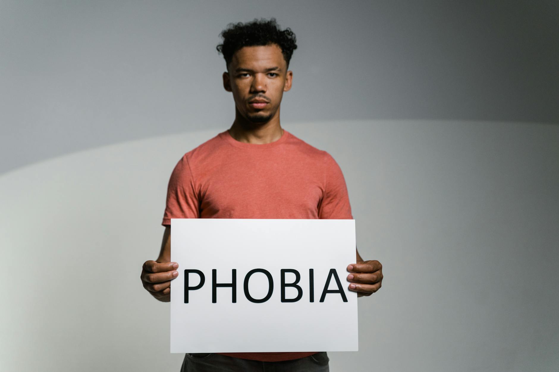A man holding a sign that reads 'PHOBIA' symbolizes awareness and feelings of fear and anxiety. - charlie sheen mental health struggles