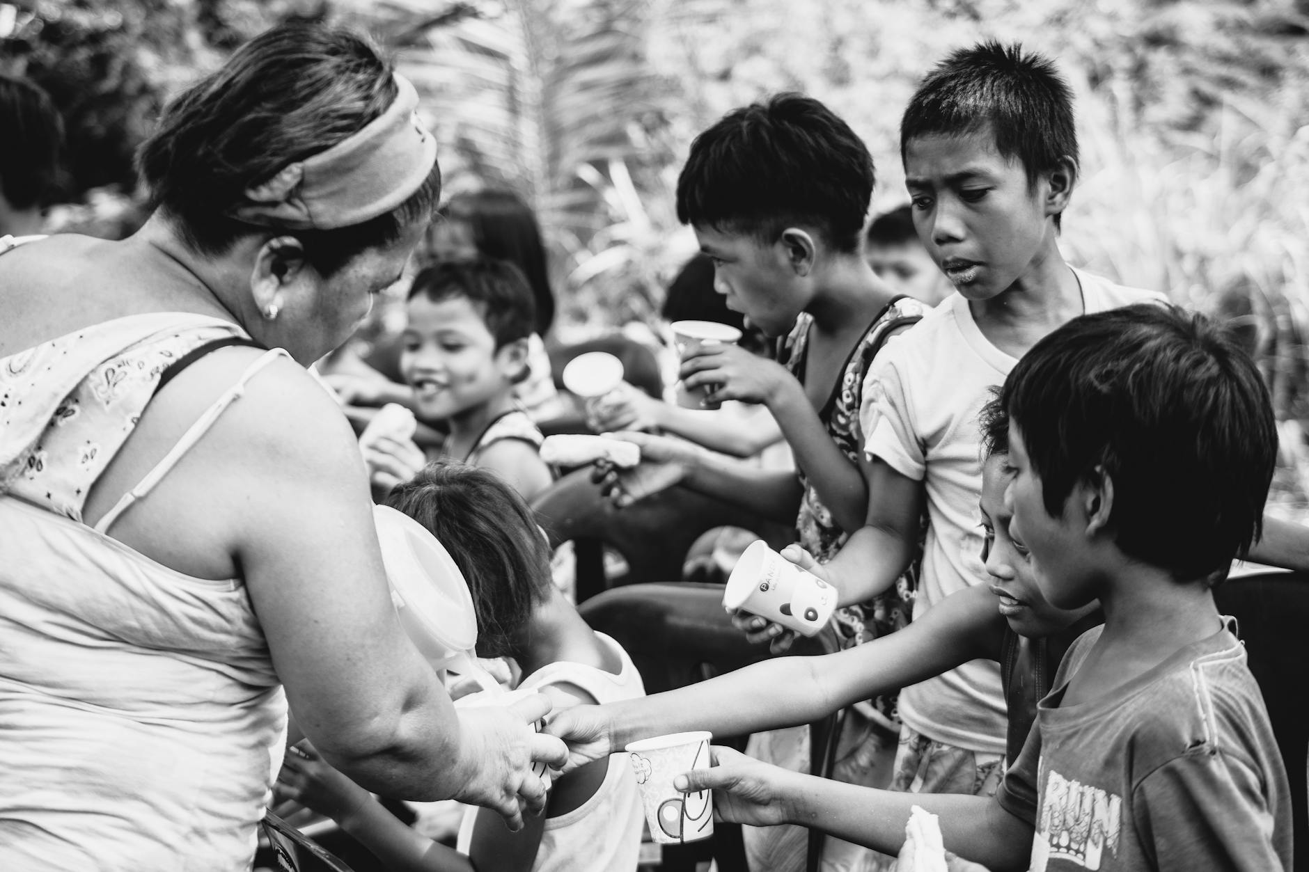 A woman hands out drinks to a group of children outdoors, illustrating community support. - children's empathy winter service